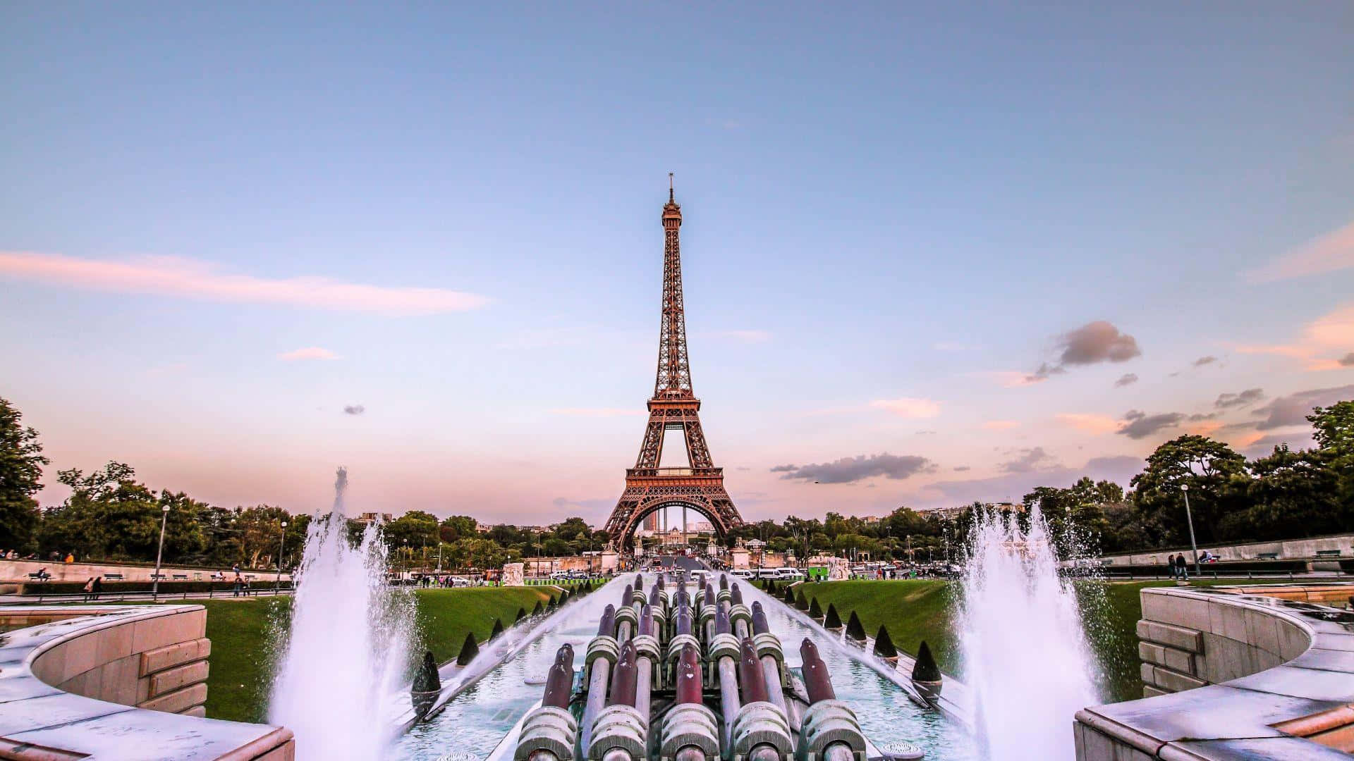 Eiffel Tower 桌布 壁紙 — 艾菲爾鐵塔在柔和的暮色天空下高聳，前景的宏偉噴泉噴出水柱。