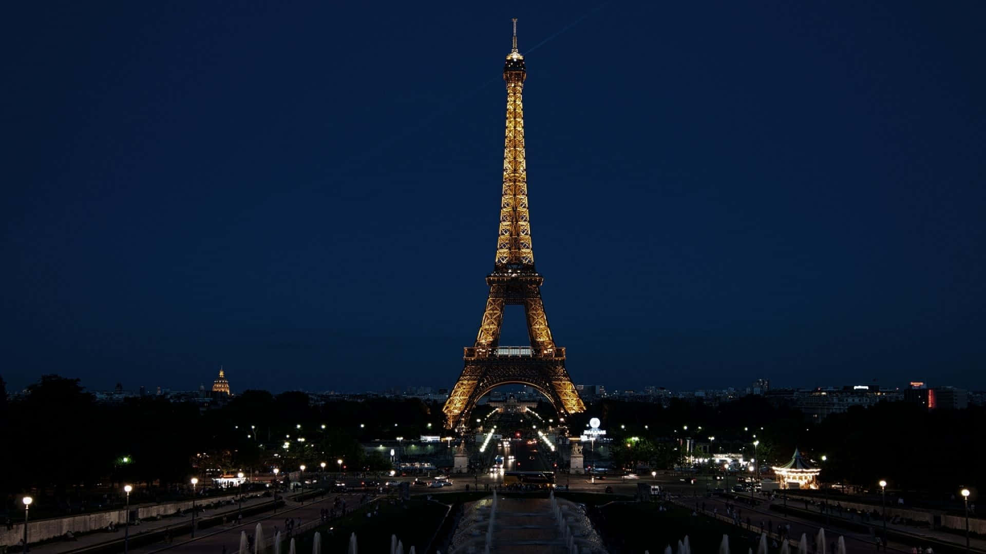 Paris Desktop 桌布 壁紙 — 艾菲爾鐵塔在深藍色的夜空中溫暖地發光，下方城市的燈光閃爍。