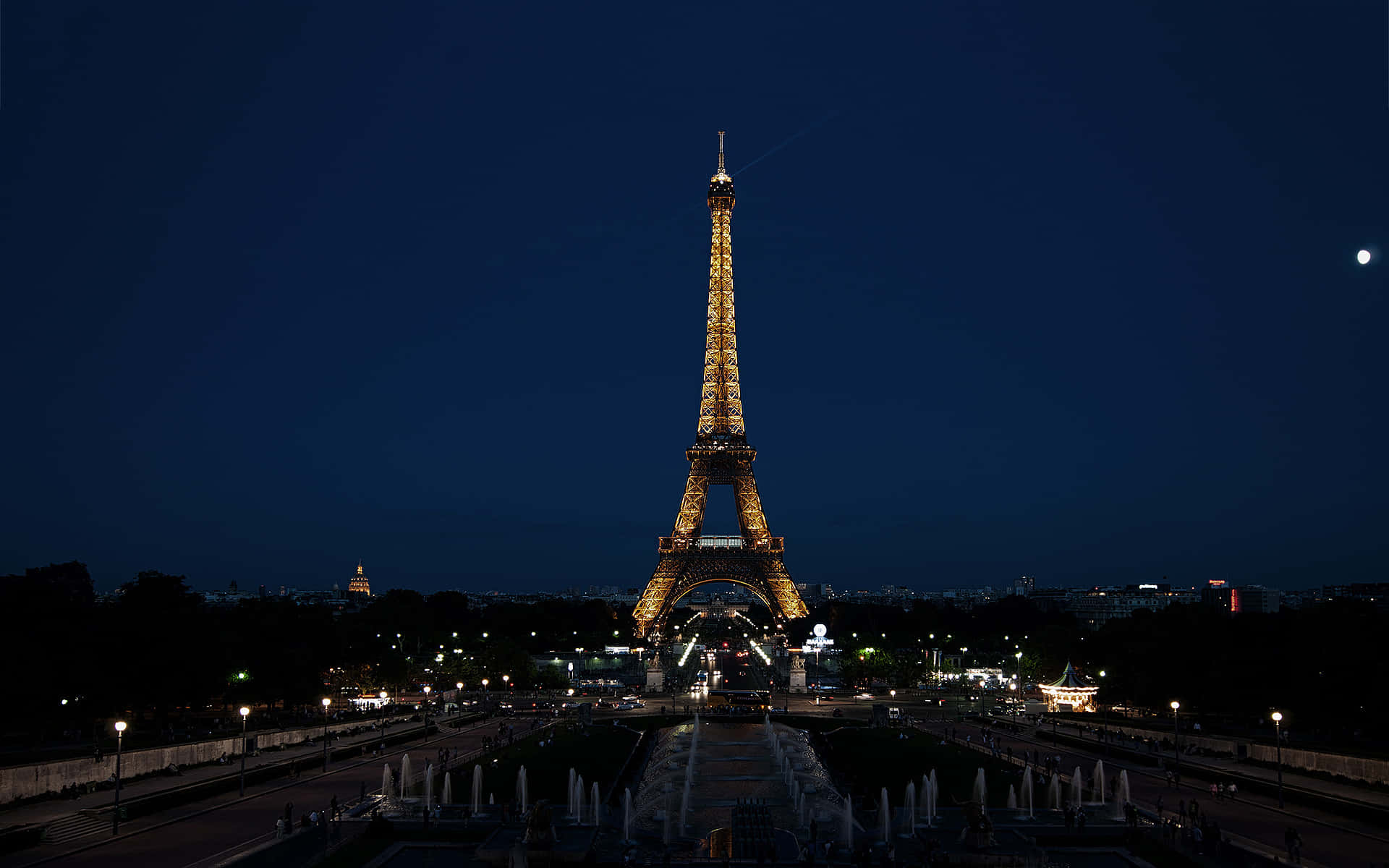 Eiffel Tower 桌布 壁紙 — 艾菲爾鐵塔在深藍色的夜空中溫暖地發光，上方可見月亮。