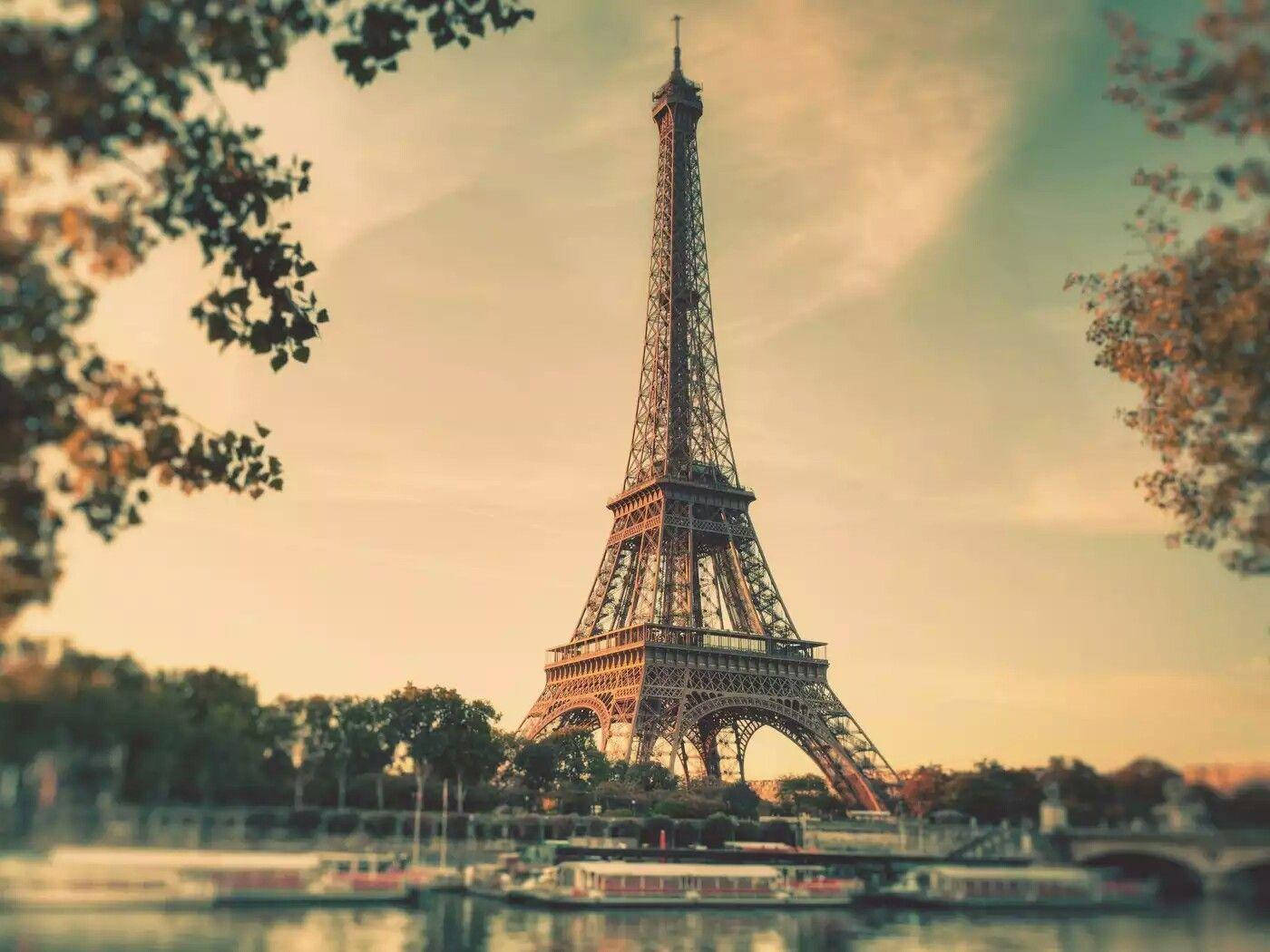 Paris Eiffel Tower 桌布 壁紙 — 艾菲爾鐵塔在溫暖的金色天空下高聳入雲，周圍環繞著秋葉和下方的河船。