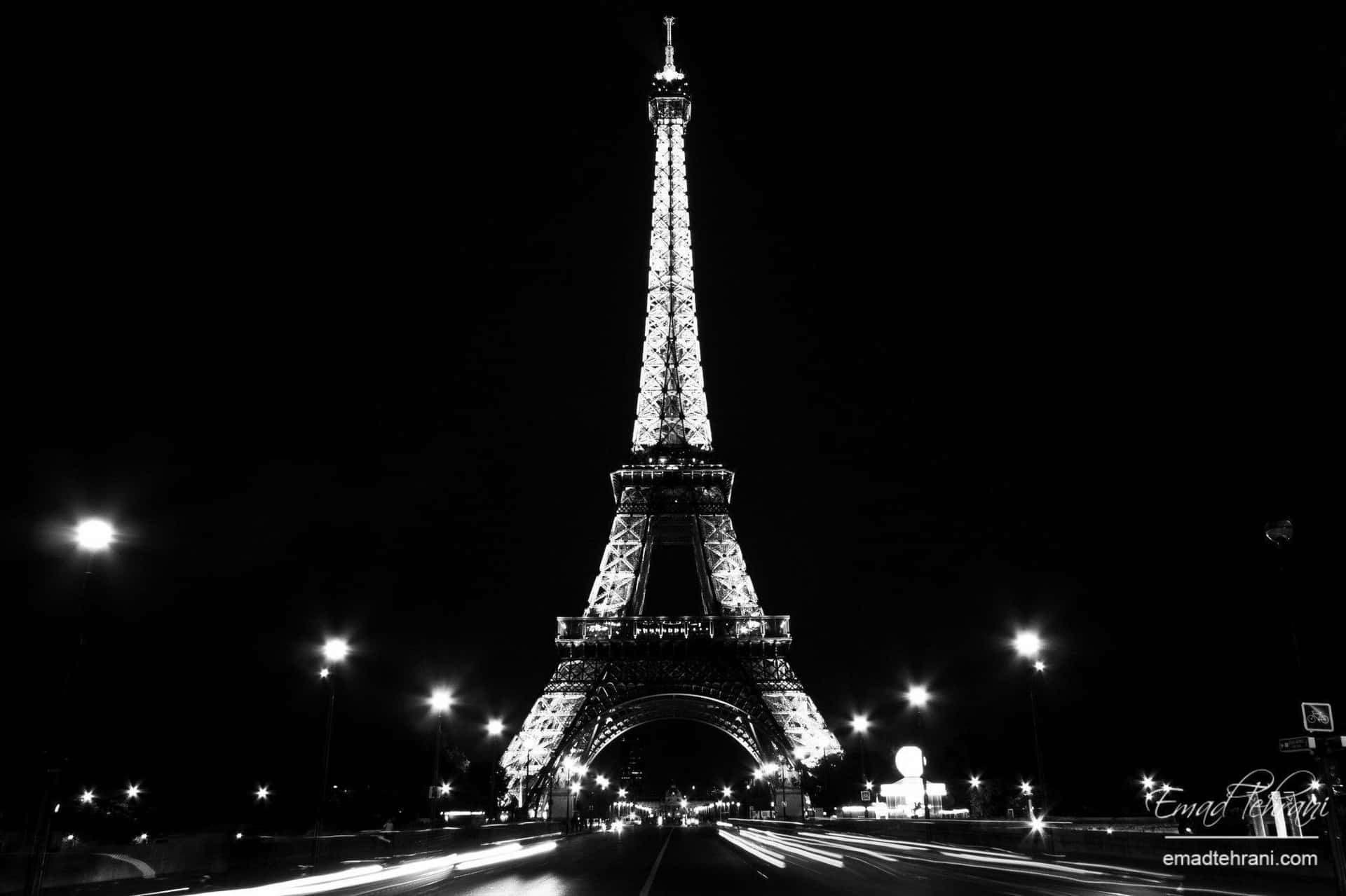 Eiffel Tower 桌布 壁紙 — 艾菲爾鐵塔在漆黑的夜空下亮起，下方有汽車燈光形成的軌跡。