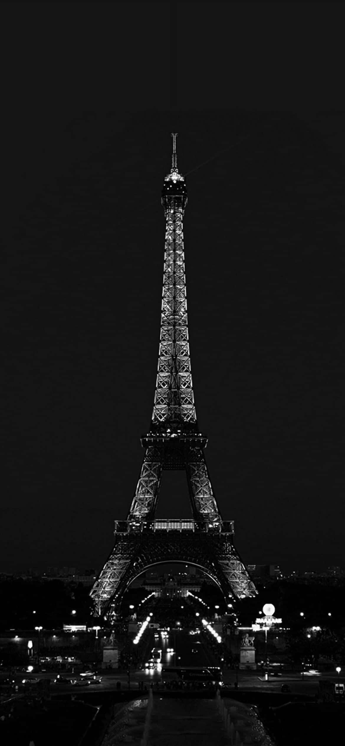 Eiffel Tower 桌布 壁紙 — 艾菲爾鐵塔在漆黑的夜空下亮起燈光，呈現出引人注目的黑白垂直拍攝效果。