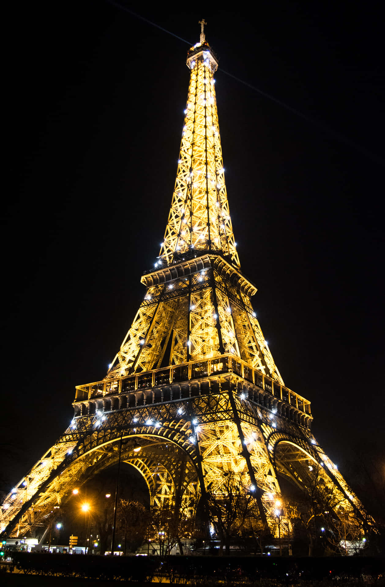 Eiffel Tower 桌布 壁紙 — 艾菲爾鐵塔在漆黑的夜空下溫暖地發光，其複雜的鐵格子結構被金色燈光燦爛照亮。