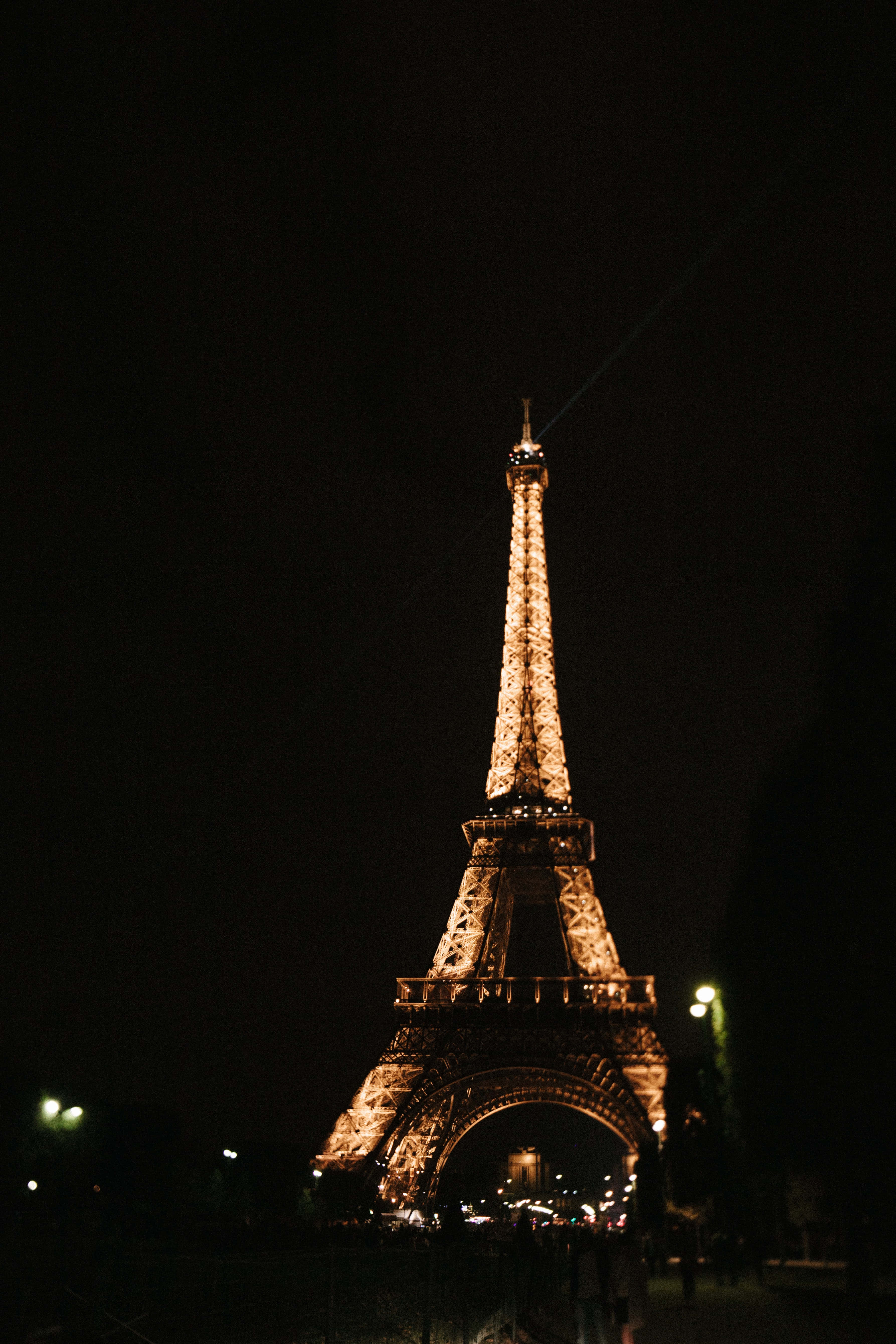 Paris At Night 桌布 壁紙 — 艾菲爾鐵塔在漆黑的夜空中溫暖地發光，遠處有柔和的城市燈光。