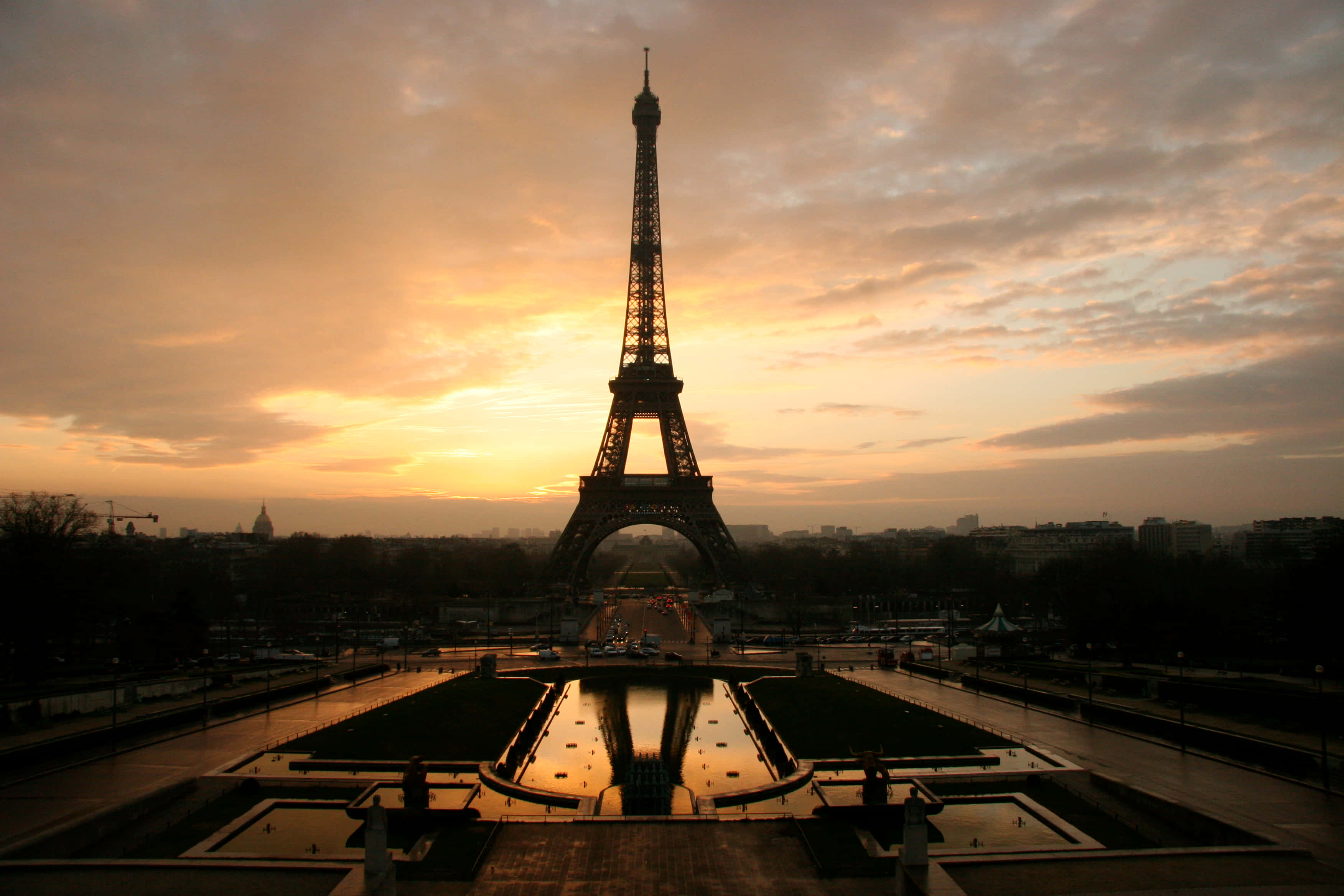 Eiffel Tower 桌布 壁紙 — 艾菲爾鐵塔在金色夕陽天空的襯托下呈現剪影，其倒影在前方的水景中閃爍。