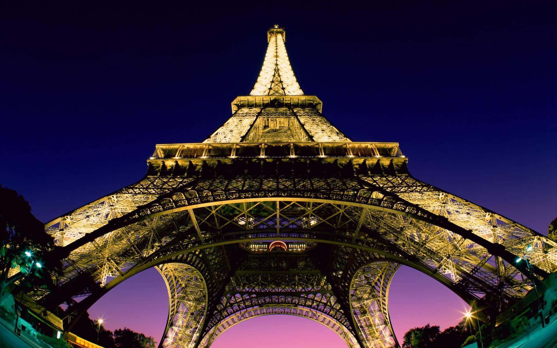Eiffel Tower 桌布 壁紙 — 艾菲爾鐵塔在黃昏時分被金色燈光照亮，背景是深藍色和紫色的天空。