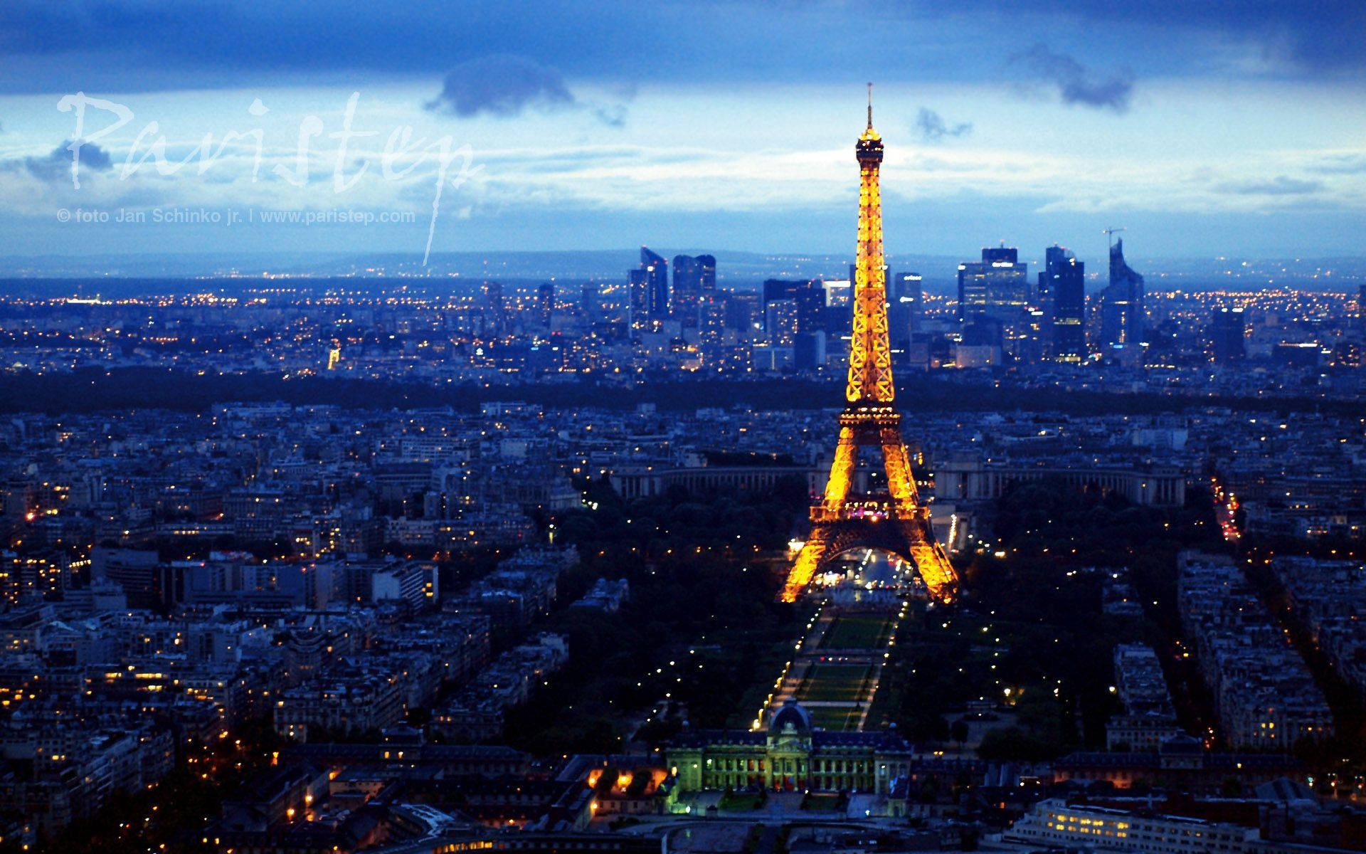 巴黎 桌布 壁紙 — 艾菲爾鐵塔在點綴著城市燈光的深藍色巴黎天際線中溫暖地發光。