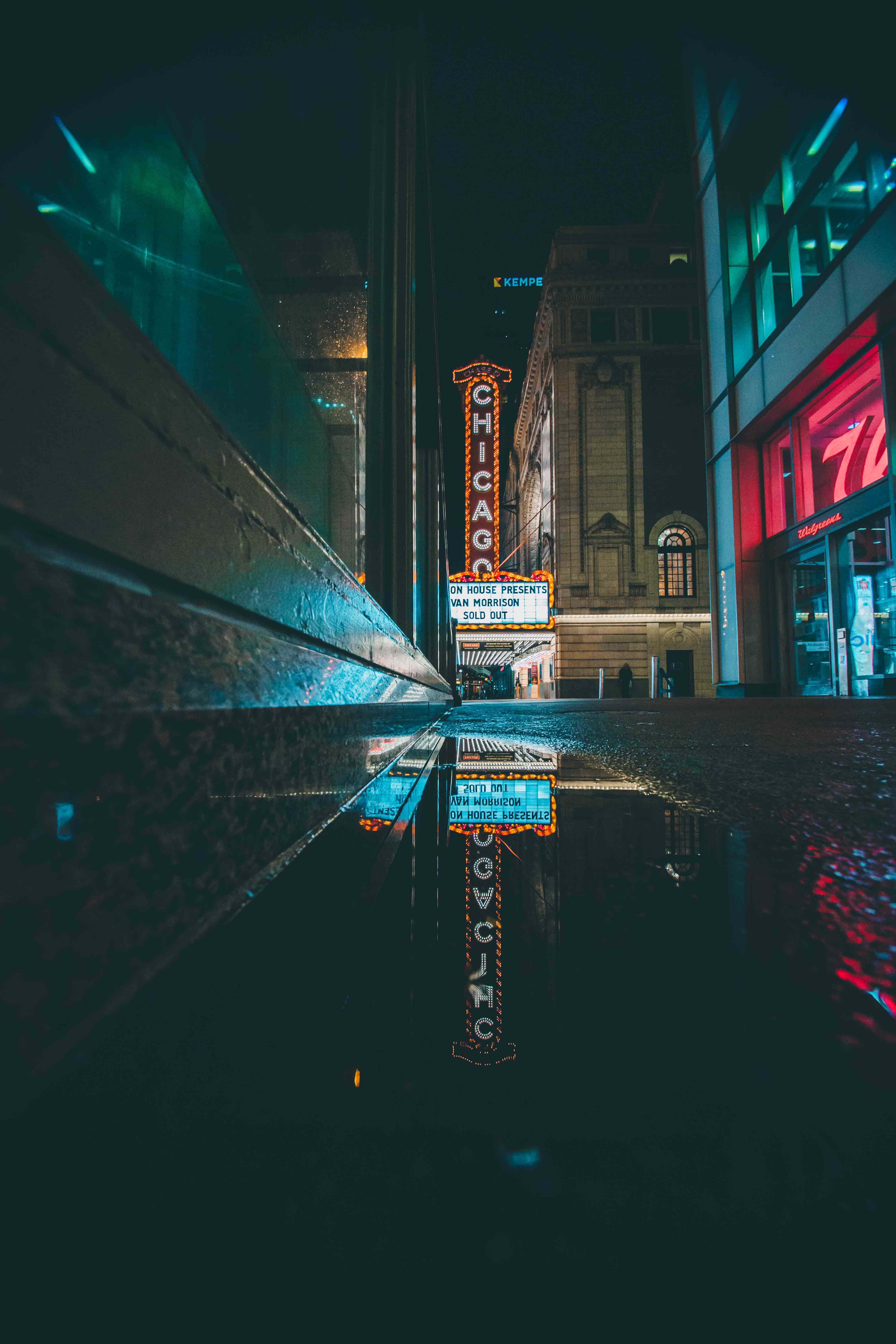 Chicago City Night 桌布 壁紙 — 芝加哥劇院的霓虹燈招牌在夜間照亮雨濕的街道，水坑中映出鮮明的倒影。