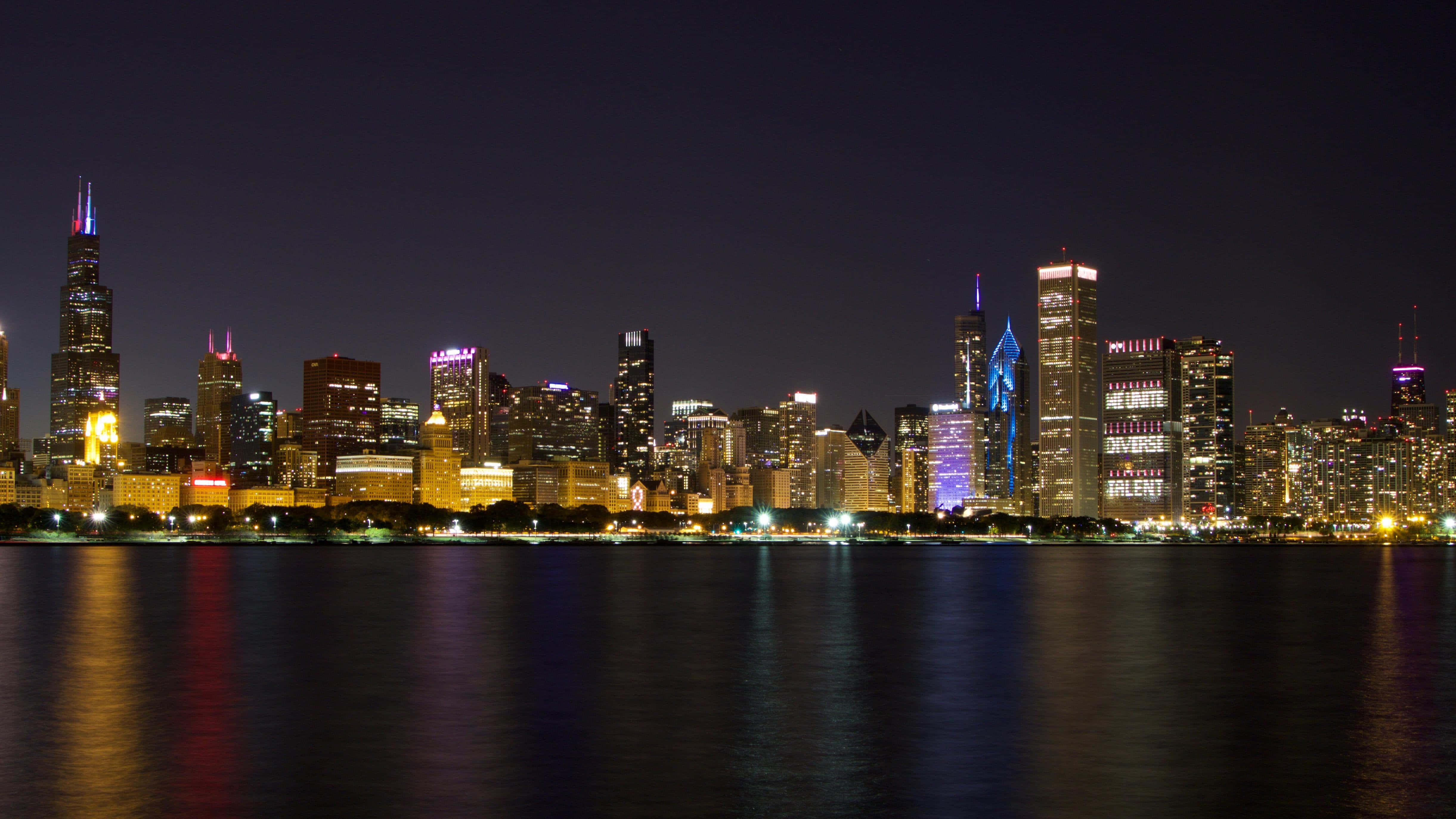 Chicago City Night 桌布 壁紙 — 芝加哥夜景，在黑暗天空下，平靜水面反射著燈火通明的摩天大樓。