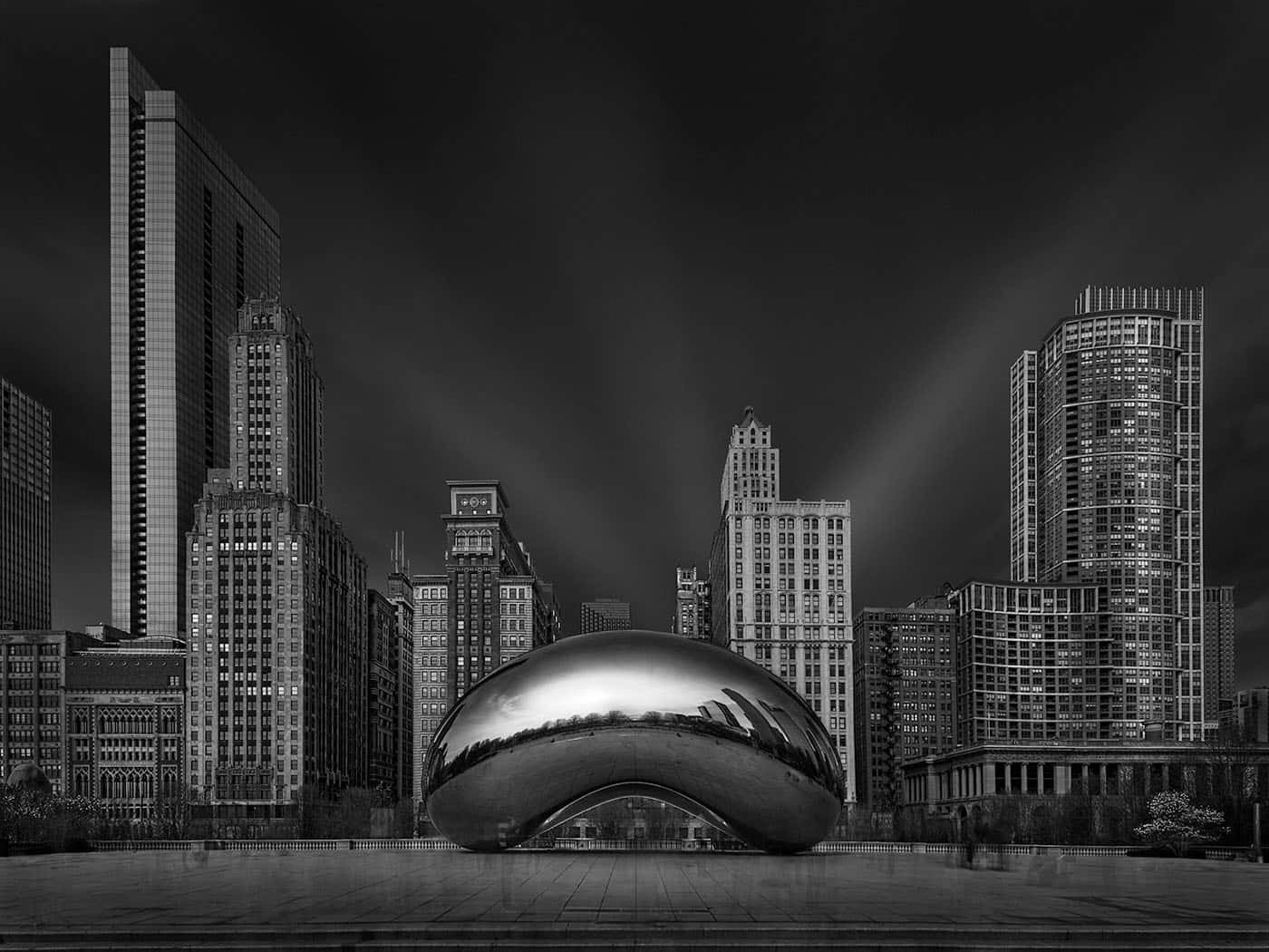 Buildings 桌布 壁紙 — 芝加哥天際線在戲劇性夜空和光束下反射於雲門雕塑的黑白照片。