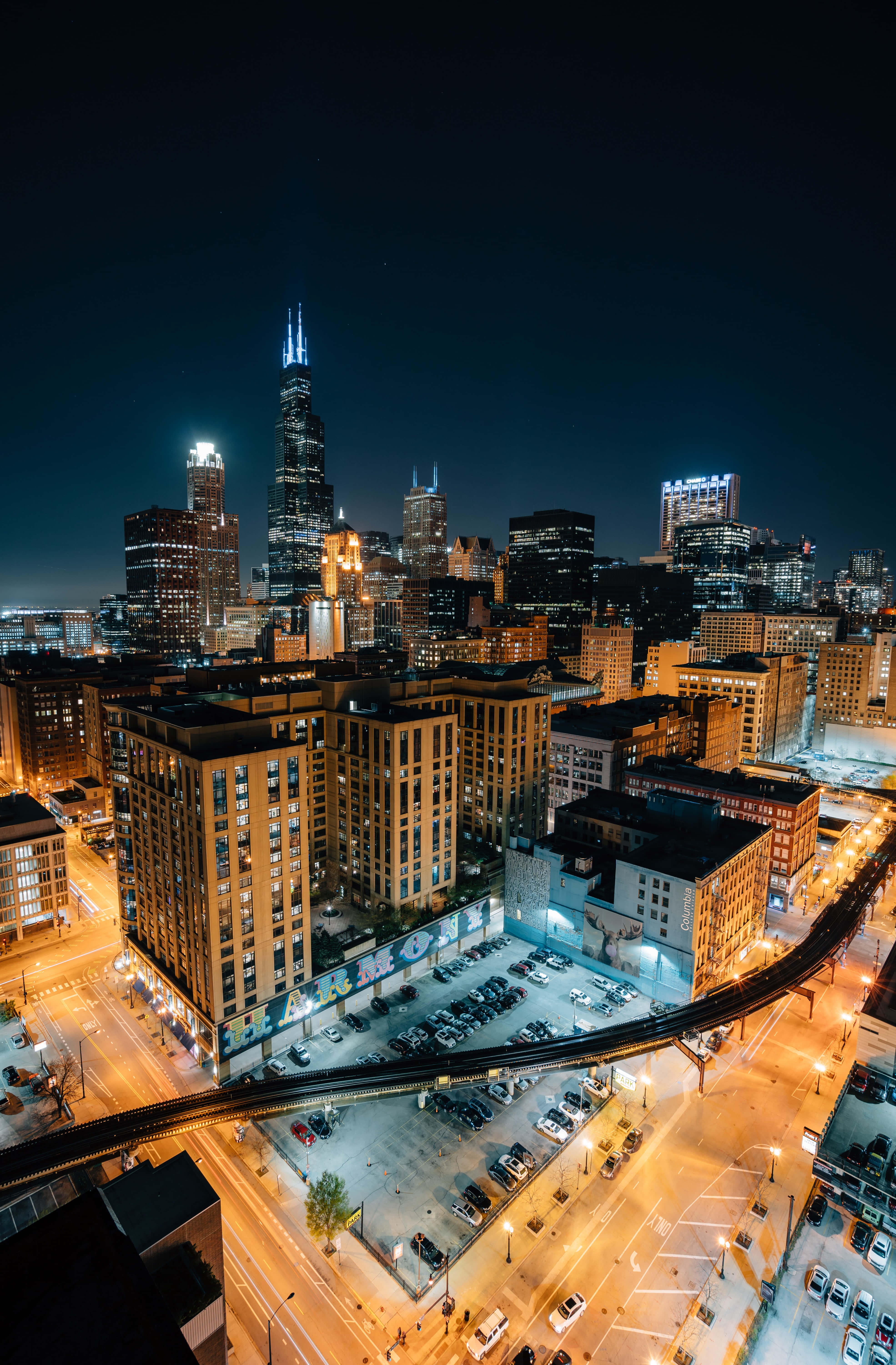 Chicago City Night 桌布 壁紙 — 芝加哥天際線的夜間空中景觀，閃爍的摩天大樓和下方燈火通明的街道。
