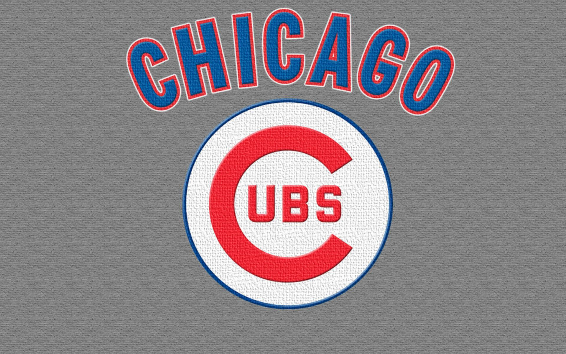 Cubs 桌布 壁紙 — 芝加哥小熊隊棒球標誌，紅、藍、白色，位於有紋理的灰色布料背景上。