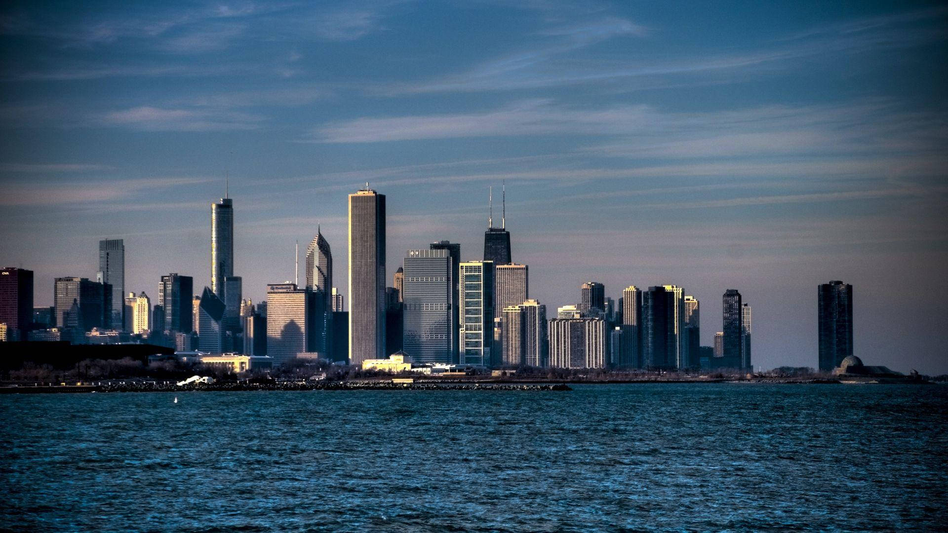 Chicago Skyline 桌布 壁紙 — 芝加哥標誌性天際線在黃昏時的全景，摩天大樓倒映在密西根湖平靜的水面上。