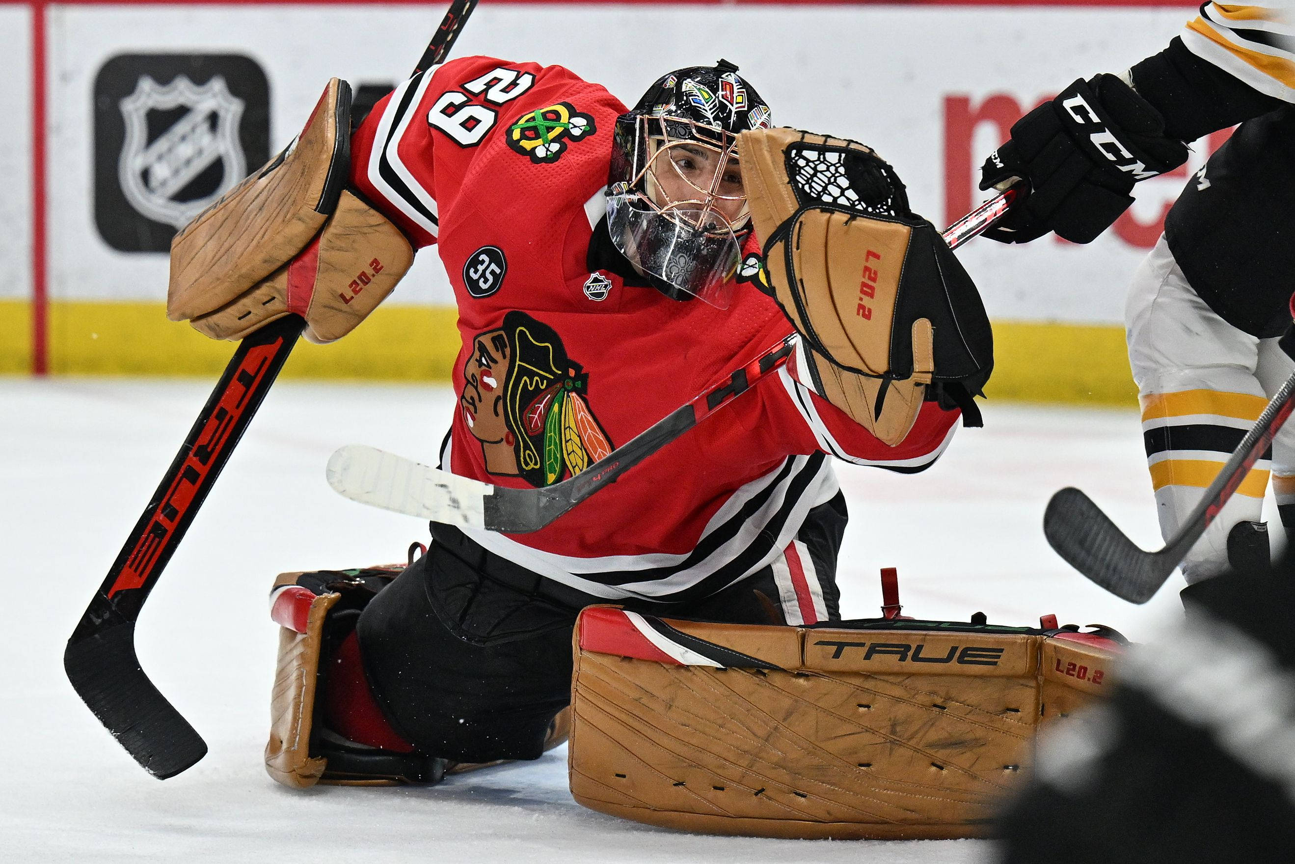 hockey 桌布 壁紙 — 芝加哥黑鷹隊的守門員身穿紅色制服，在激烈的NHL比賽中於冰上做出戲劇性的撲救。