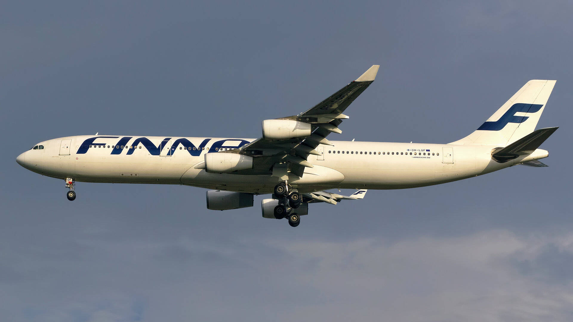 飛機 桌布 壁紙 — 芬蘭航空一架白色和藍色塗裝的空中巴士A330正在放下起落架，在柔和藍天和零星雲朵的背景下下降。