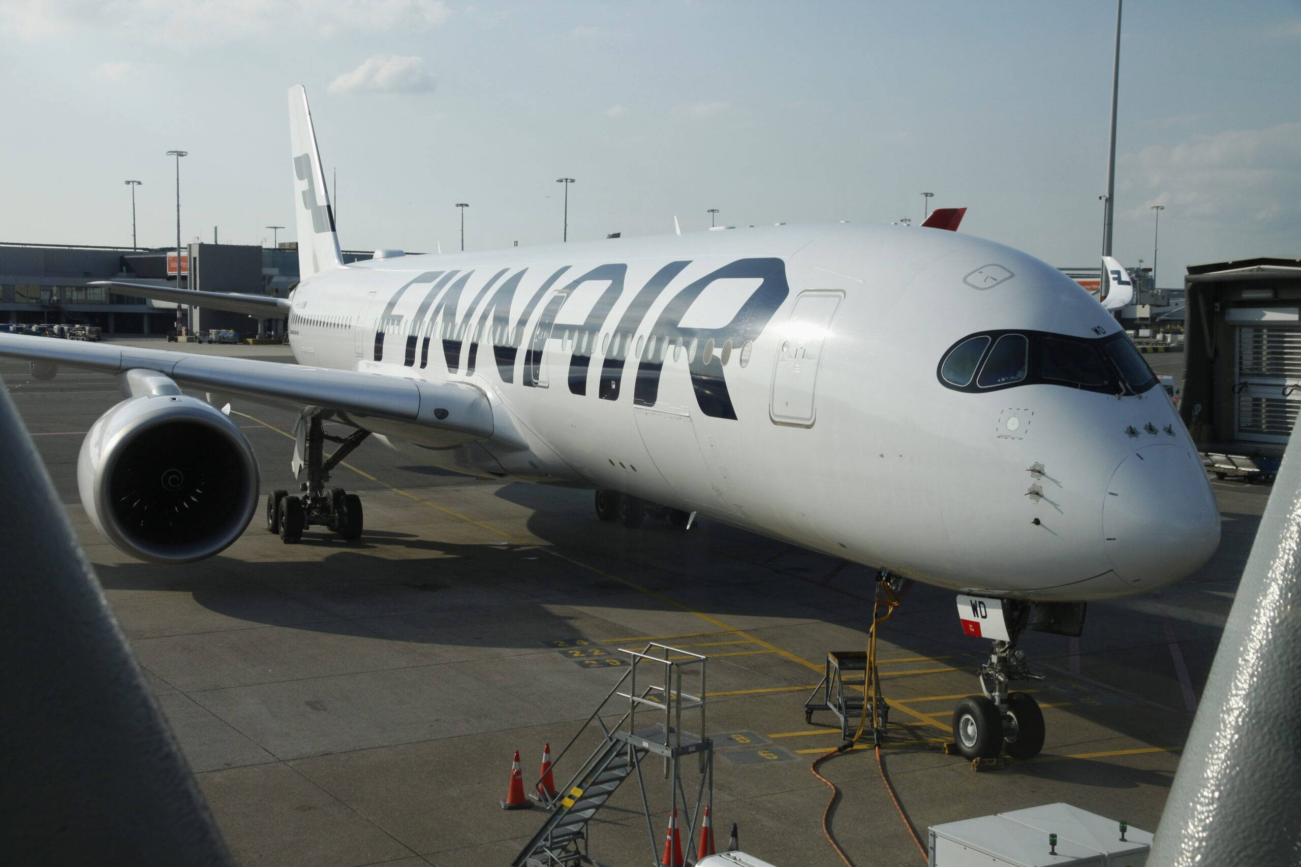 飛機 桌布 壁紙 — 芬蘭航空的空中巴士A350停泊在機場閘口，地面工作人員設備齊全，頭頂是清澈的藍天。