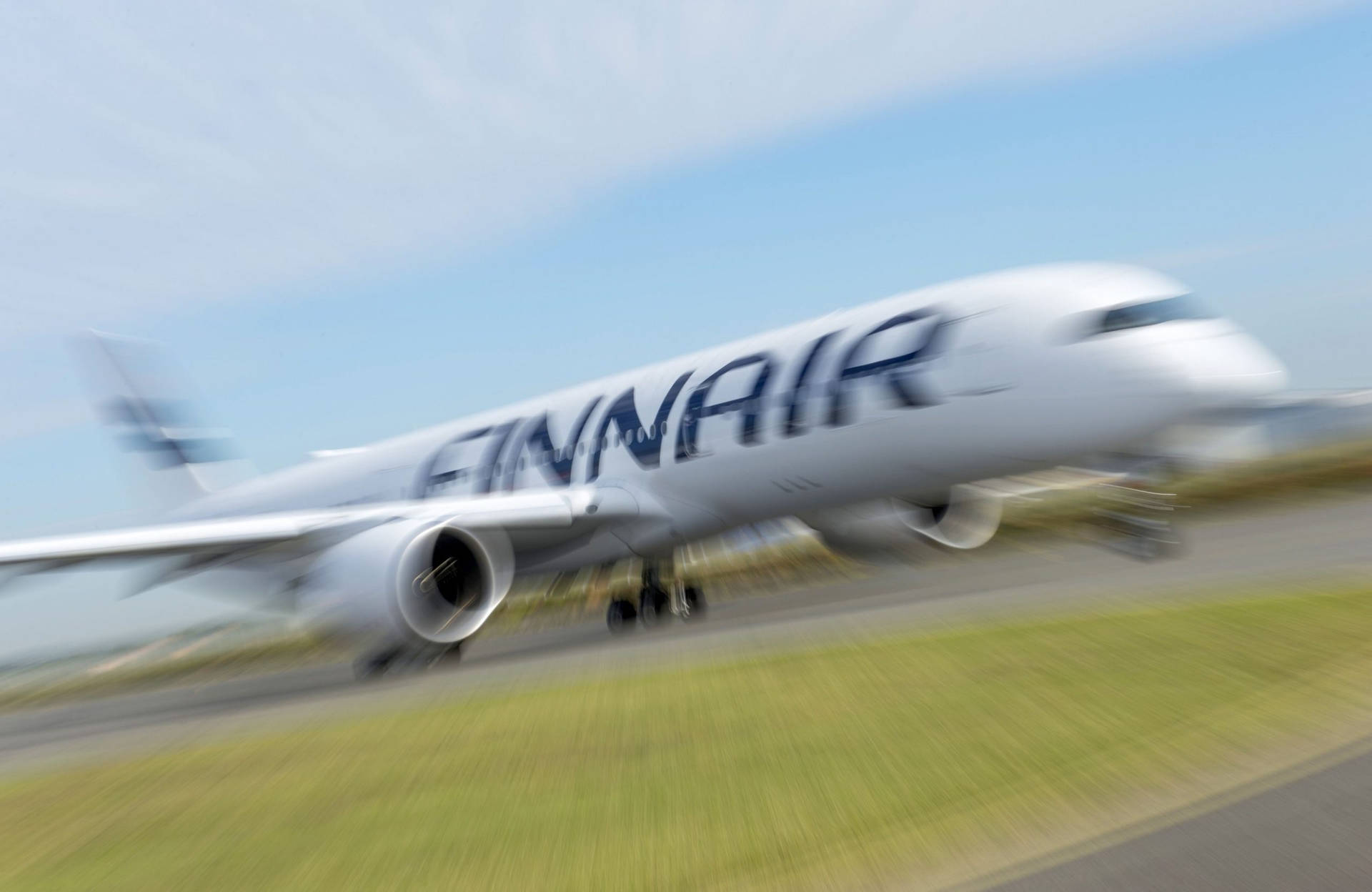  壁紙 — 芬蘭航空的飛機在晴朗藍天下於跑道上高速行駛，形成動態模糊。
