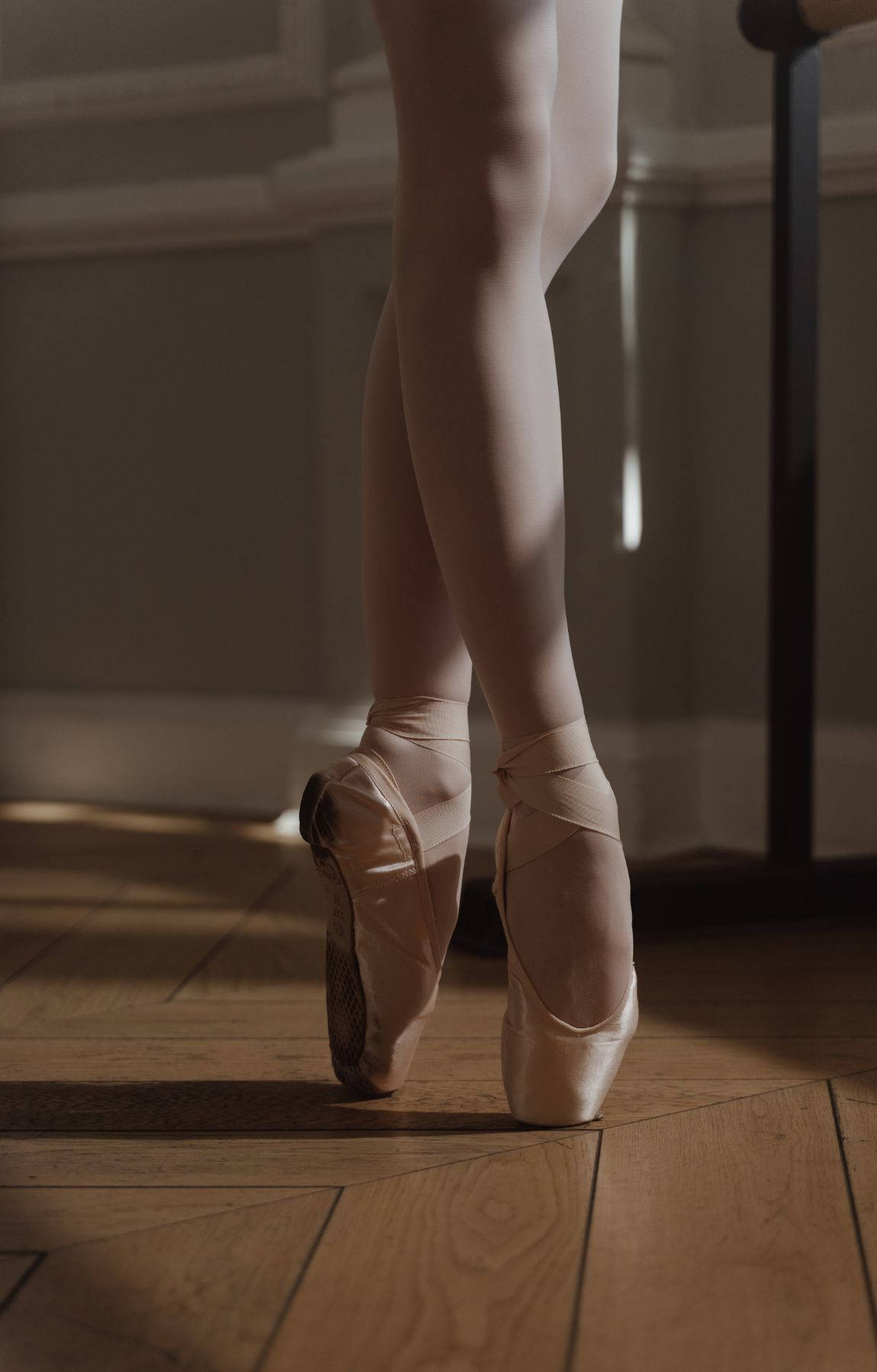 ballerina 桌布 壁紙 — 芭蕾舞者的雙腿穿著足尖鞋，優雅地立在古典舞蹈室的陽光木地板上。