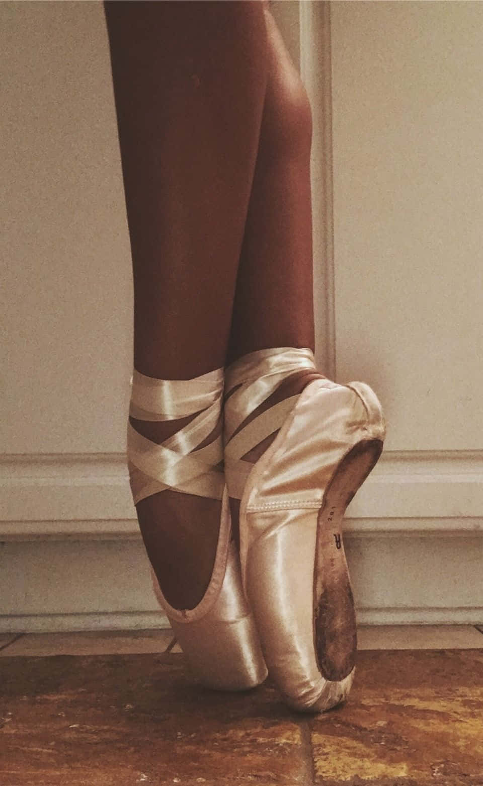 Ballet 桌布 壁紙 — 芭蕾舞者穿著磨損緞面足尖鞋的腳部特寫，靠牆休息在木地板上。