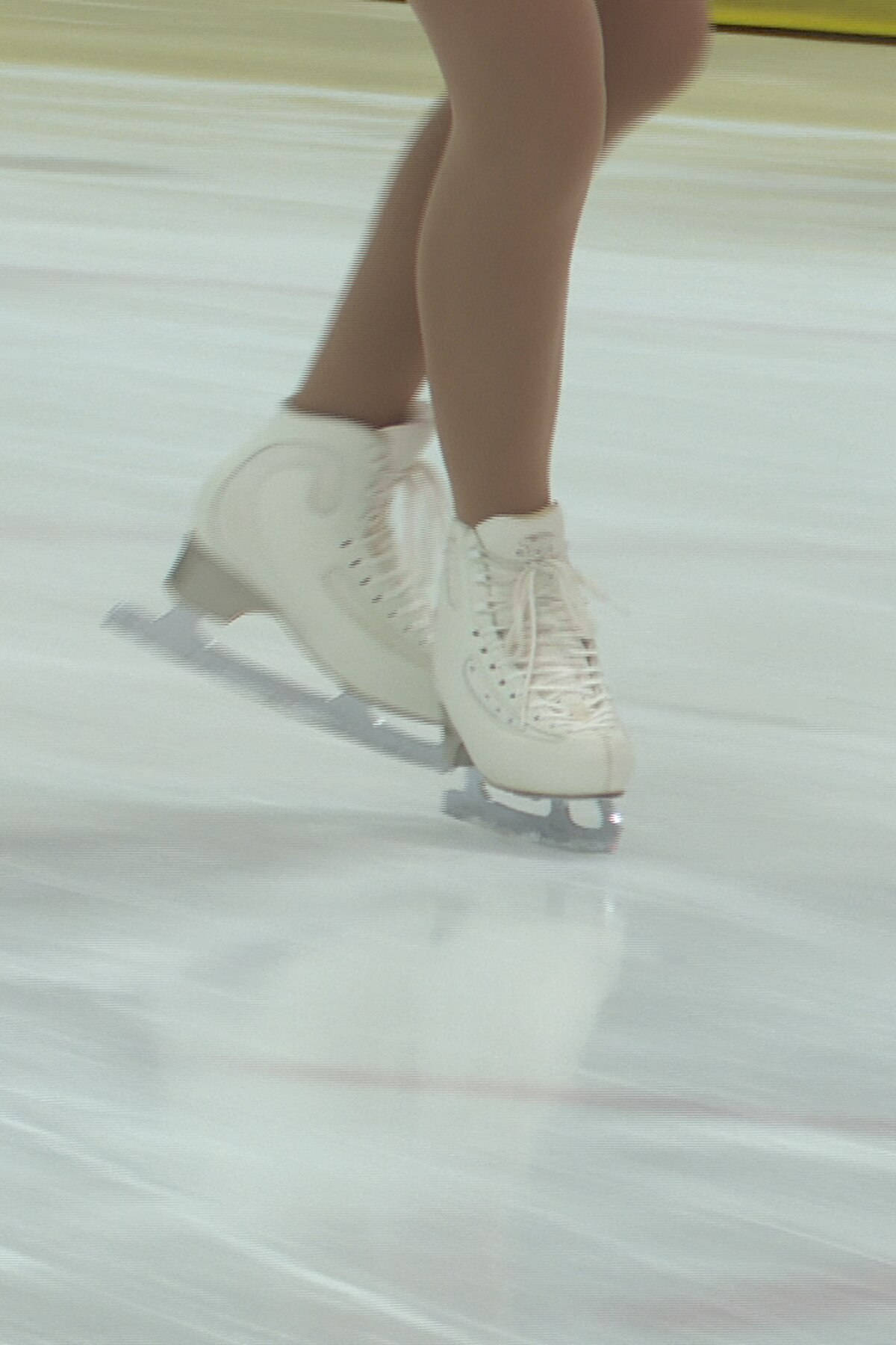 Ice Skating 桌布 壁紙 — 花式滑冰者白色靴子在光滑冰面上快速滑行的特寫，帶有動態模糊效果。