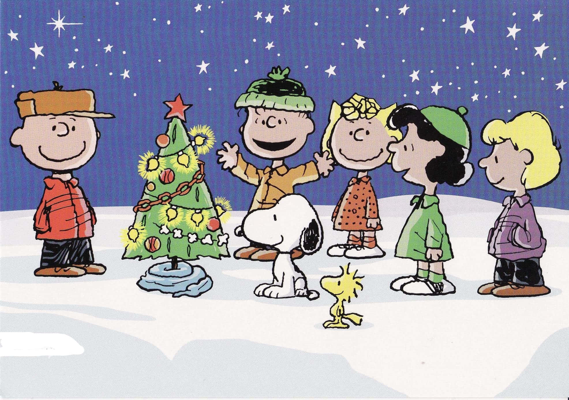 Peanuts Christmas 桌布 壁紙 — 花生漫畫角色們聚集在裝飾好的聖誕樹周圍，背景是雪地景觀和繁星點點的夜空。