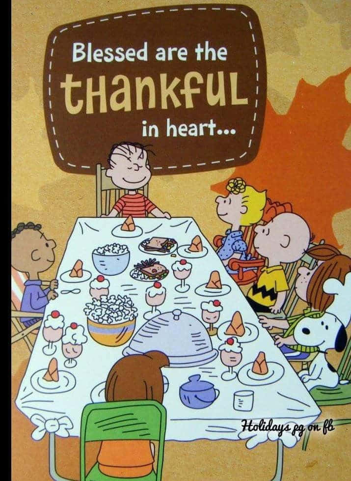 Charlie Brown Thanksgiving 桌布 壁紙 — 花生漫畫角色聚集在節日餐桌旁，上方標語寫著「心裡感恩的人有福了…」，背景是溫暖的秋日色調。