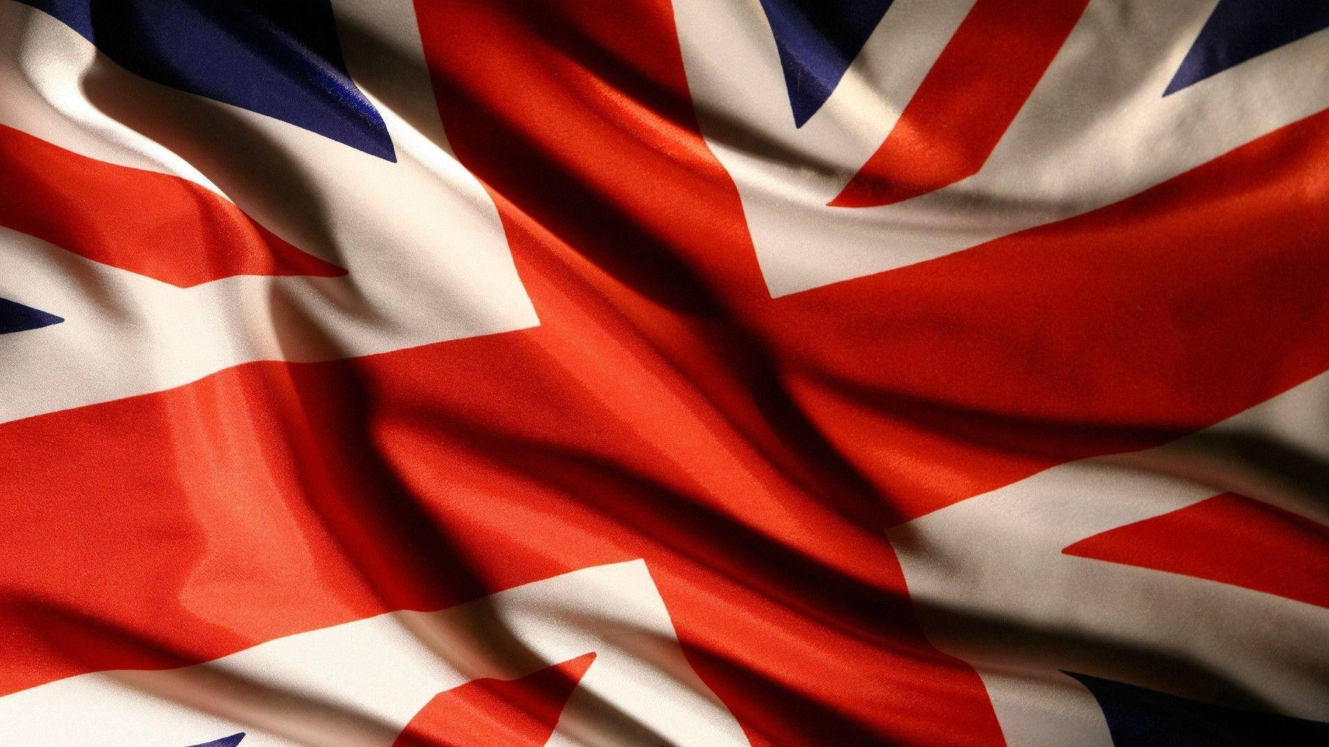 Flag 桌布 壁紙 — 英國國旗的微距特寫，帶有紋理，紅、白、藍三色在動態褶皺中飄揚。