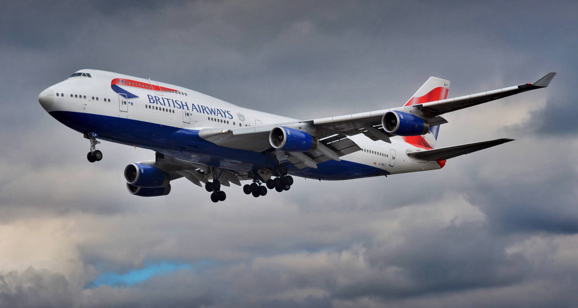  壁紙 — 英國航空的波音747在戲劇性的多雲天空中翱翔，起落架放下。