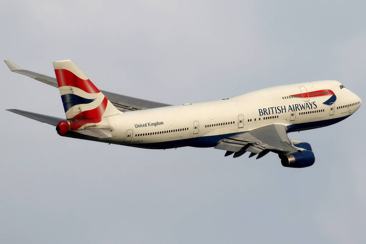 壁紙 — 英國航空的波音747在蒼白的多雲天空中翱翔，其標誌性的紅白藍尾翼清晰可見。