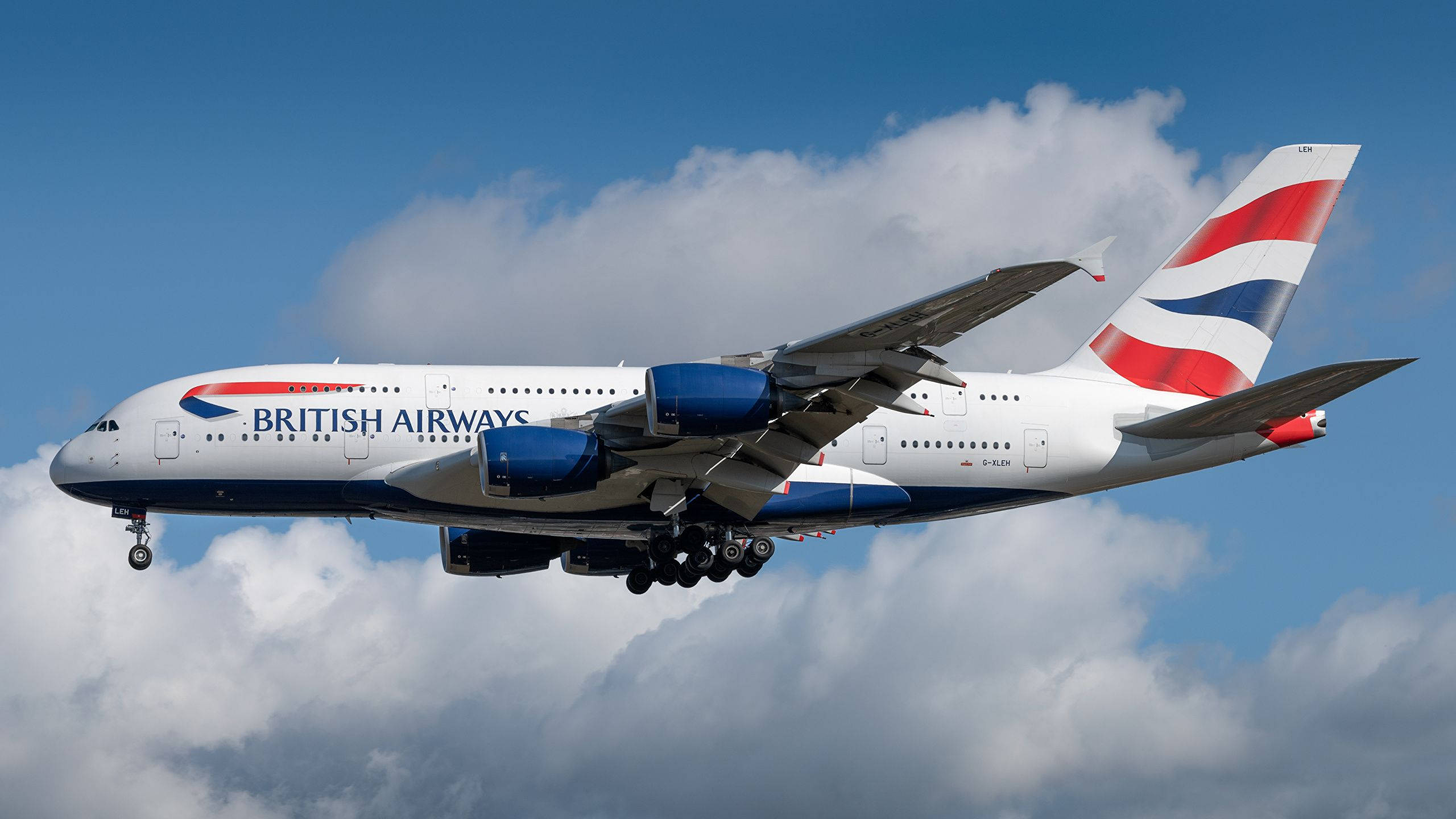飛機 桌布 壁紙 — 英國航空的空中巴士A380在明亮的藍天中翱翔，起落架下方有蓬鬆的白雲。