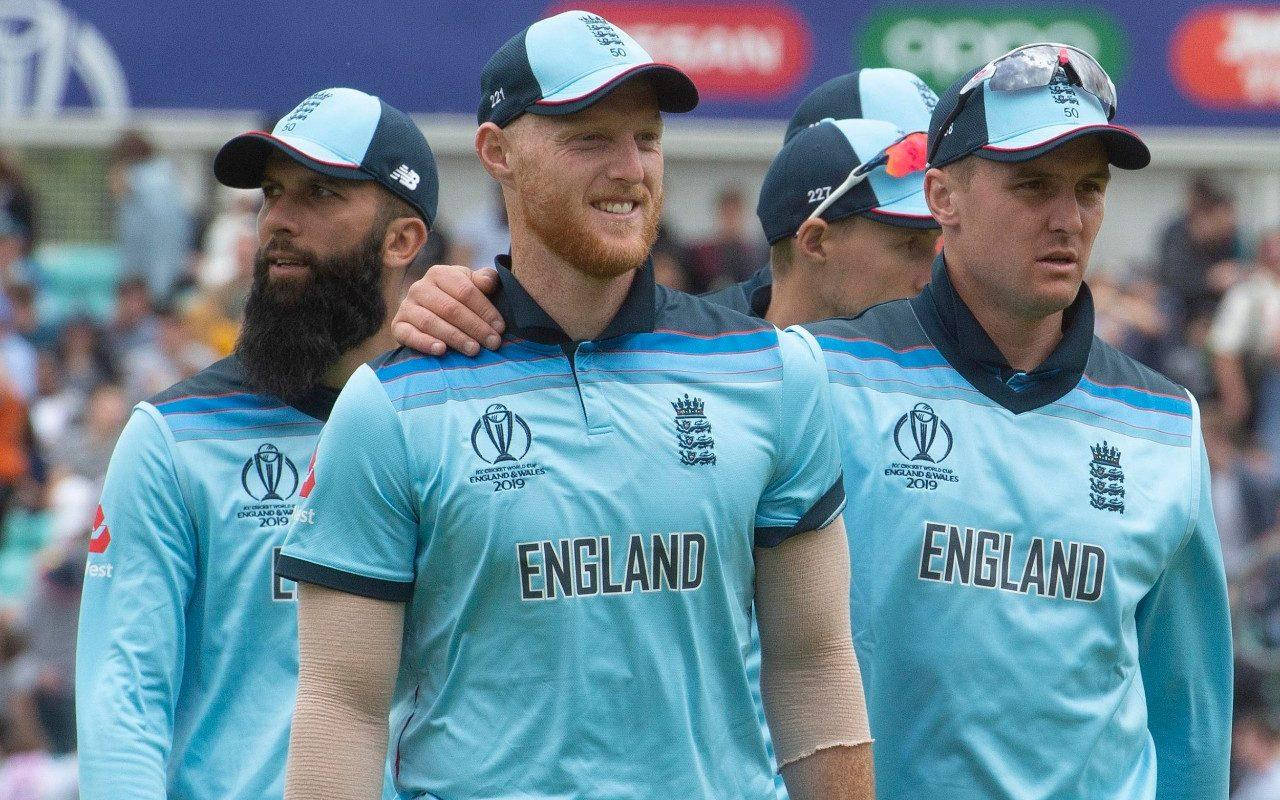 England Cricket 桌布 壁紙 — 英格蘭板球隊球員身穿淺藍色球衣，在陽光明媚的日子裡站在體育場，背景有球迷。