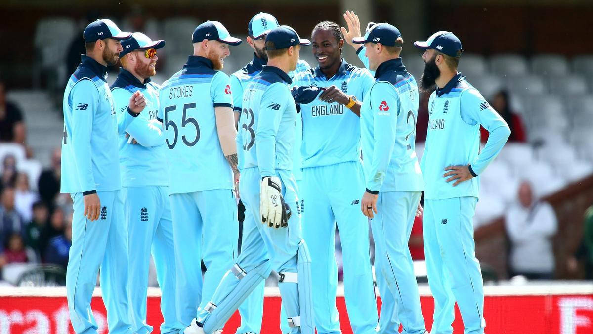 England Cricket 桌布 壁紙 — 英格蘭板球隊身穿淺藍色制服在陽光明媚的球場上一起慶祝。