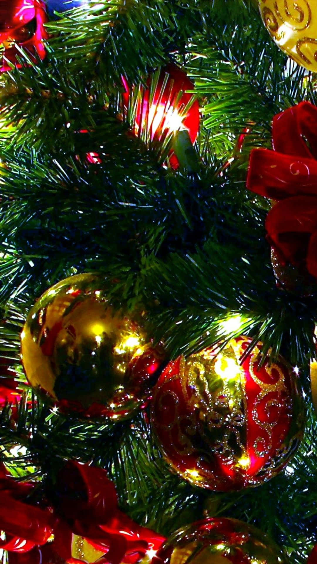 Christmas Cell Phone 桌布 壁紙 — 茂密綠色聖誕樹的特寫，裝飾著閃亮的金色和紅色飾品及絲帶，在節日燈光下閃耀。