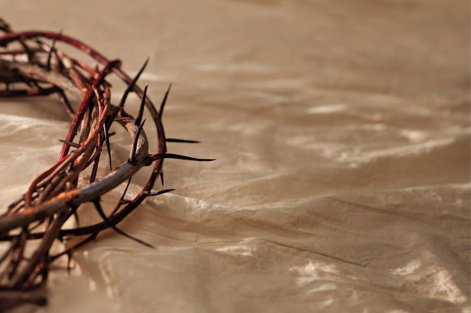 Holy Week 桌布 壁紙 — 荊棘冠冕放在柔軟溫暖光線下的皺褶米色布料上。