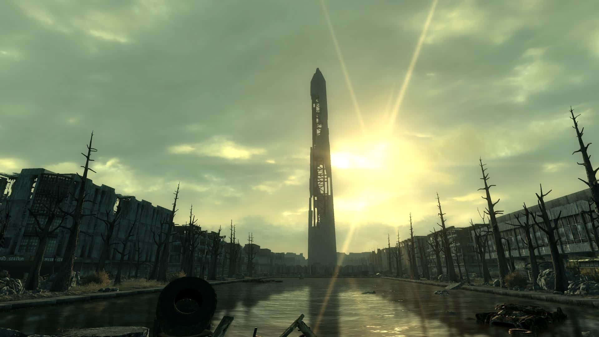 Fallout 4 Wasteland 桌布 壁紙 — 荒涼的末日後城市景觀，一座高聳的巨石矗立在廢墟建築和枯樹之間，在朦朧的太陽下。