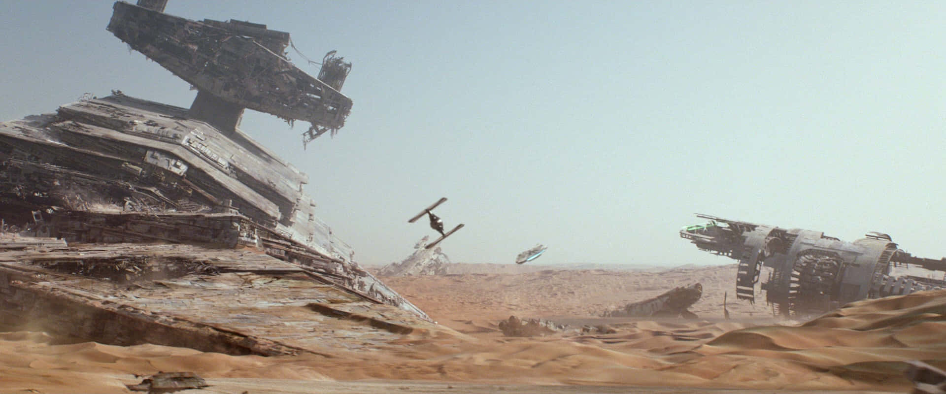 Jakku 桌布 壁紙 — 荒涼的沙漠景觀，巨大的廢棄太空船和小型飛行器在朦朧的天空下穿梭其間。