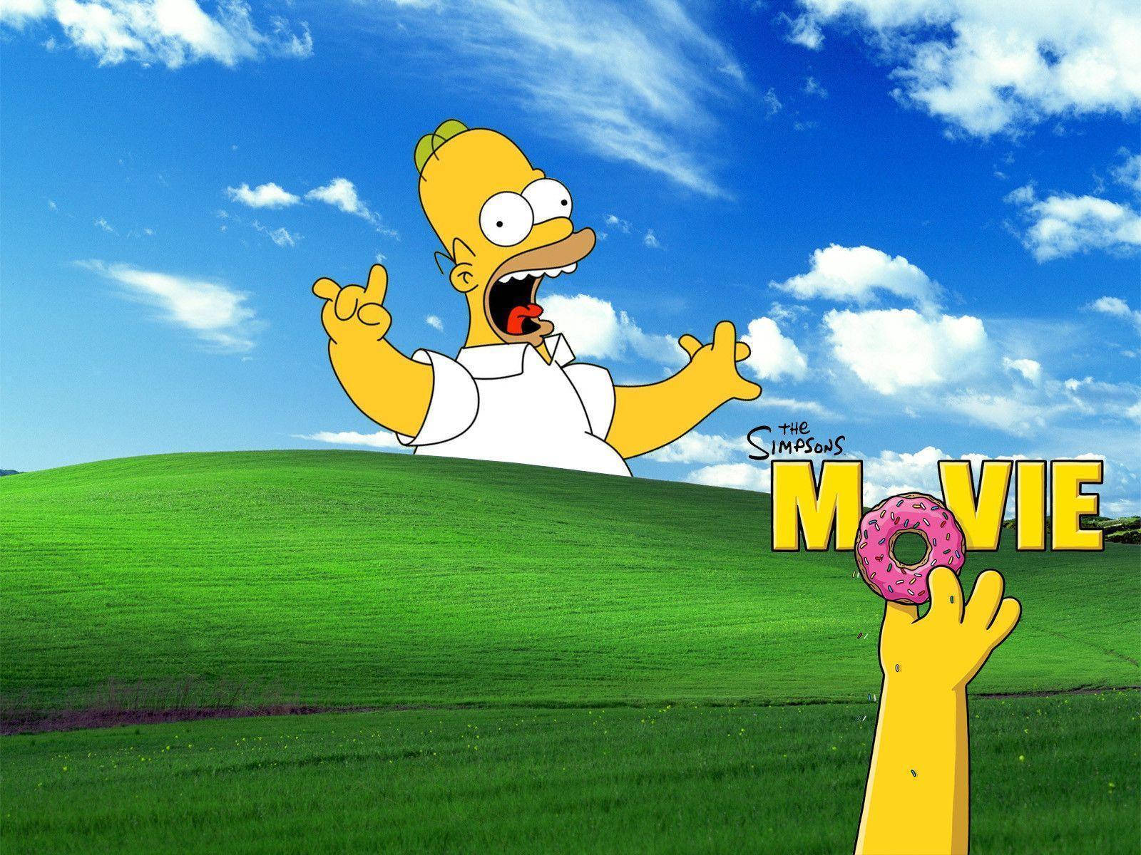 homer 桌布 壁紙 — 荷馬·辛普森從藍天下的綠色山丘彈出，拿著一個粉紅色糖霜甜甜圈，附近有『The Simpsons Movie』的文字。