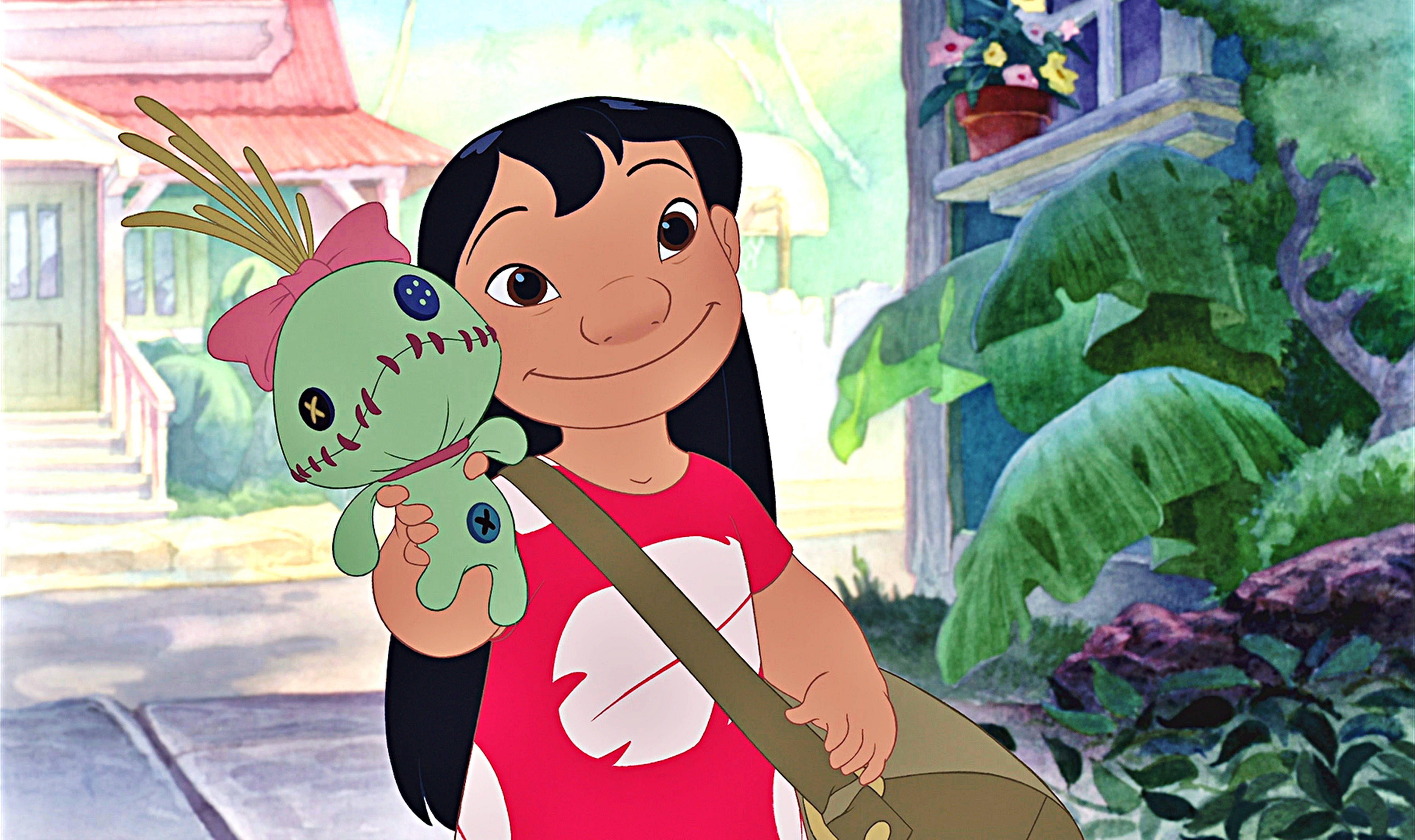 lilo 桌布 壁紙 — 莉蘿在陽光明媚的熱帶庭院中，手持一個縫製的綠色娃娃，上面繫著粉紅色蝴蝶結，背景是茂密的綠植和房屋。