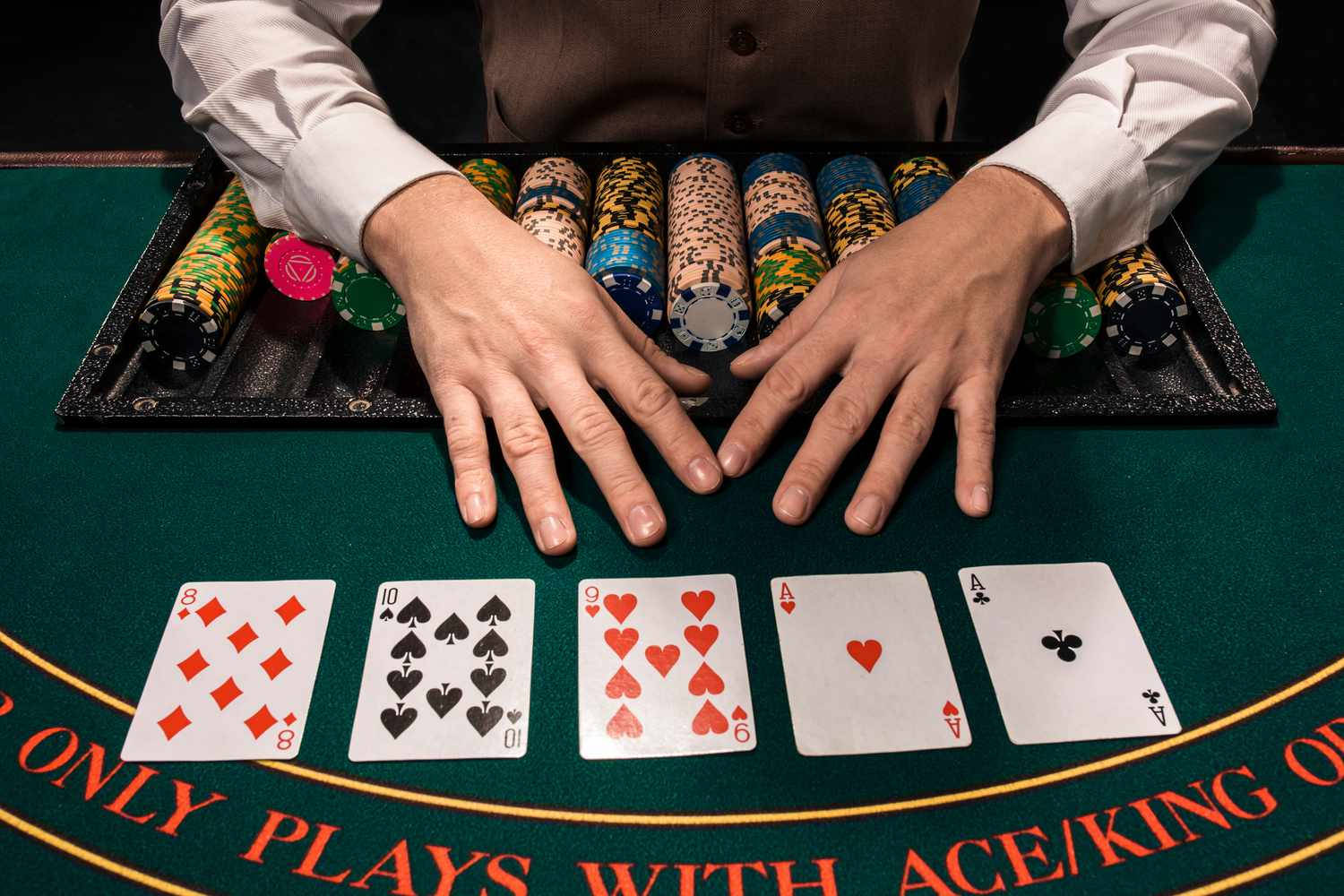 Playing Cards 桌布 壁紙 — 莊家的手放在綠色賭桌上的籌碼和正面朝上的撲克牌上，並有粗體紅色文字。