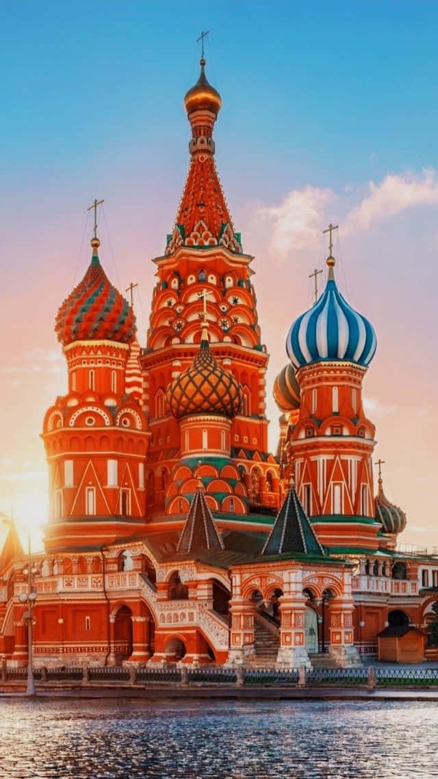 Moscow 桌布 壁紙 — 莫斯科的聖瓦西里大教堂在溫暖的夕陽光照下閃耀，光線反射在下面的河流上。