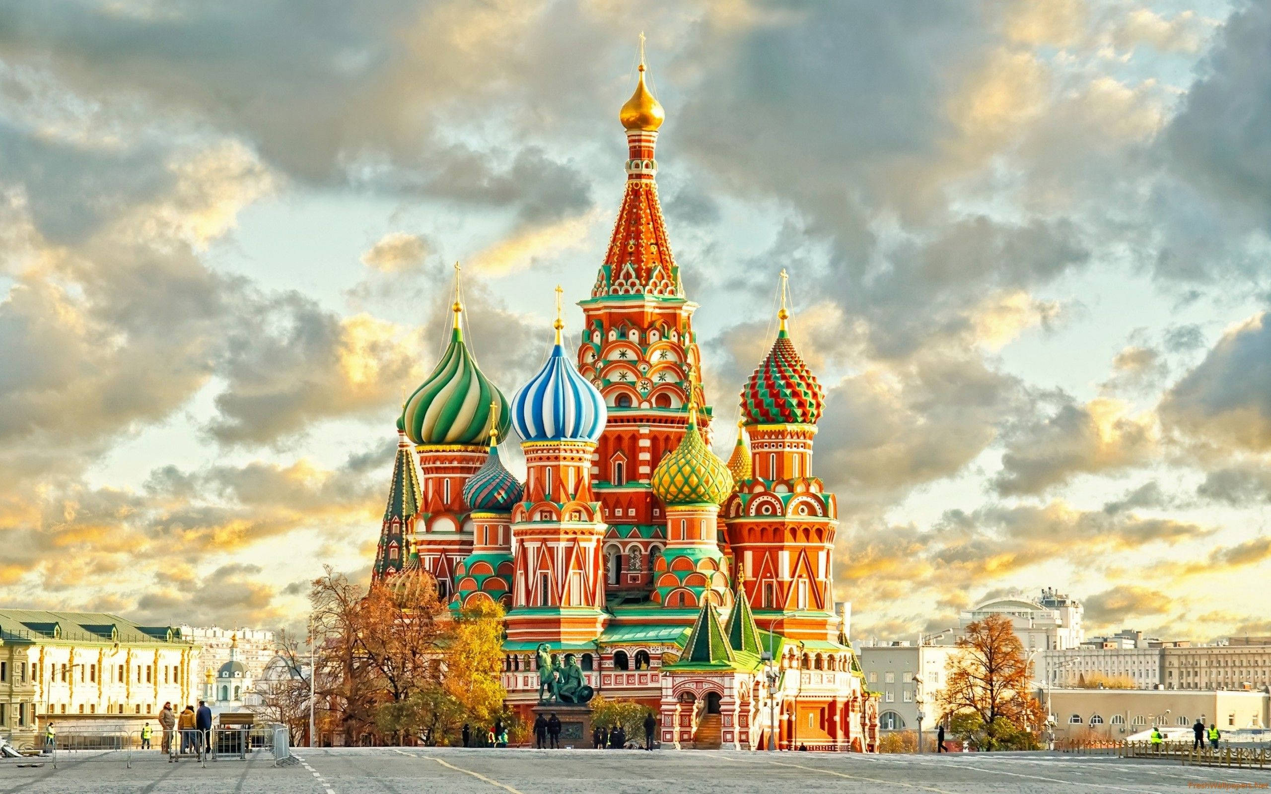 Russia 桌布 壁紙 — 莫斯科聖瓦西里大教堂在戲劇性的日落天空下閃耀，伴隨著金色的雲彩和秋天的樹木。