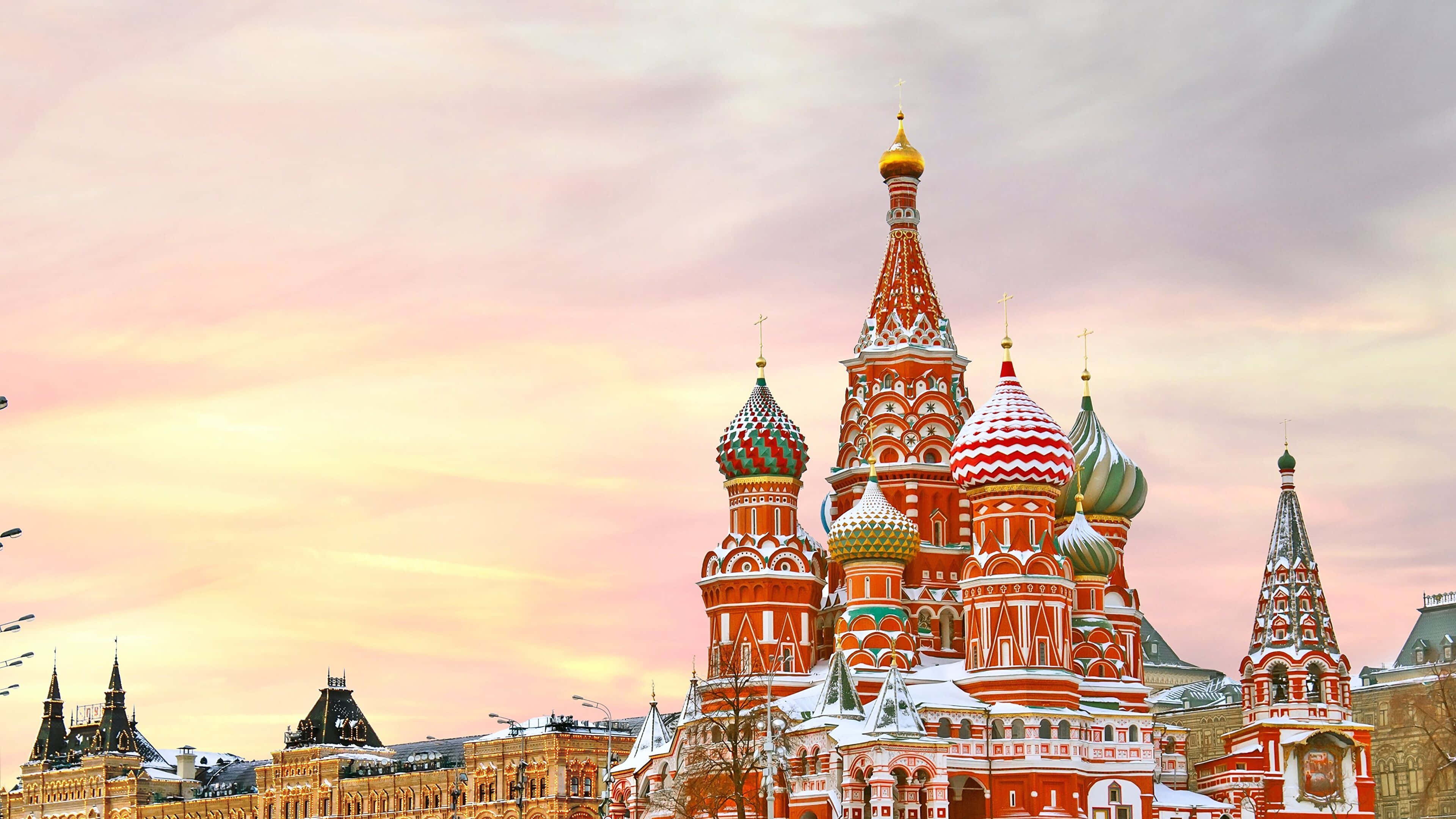 Russian 桌布 壁紙 — 莫斯科聖瓦西里大教堂在柔和的粉紅色和橙色暮色天空下被雪覆蓋。