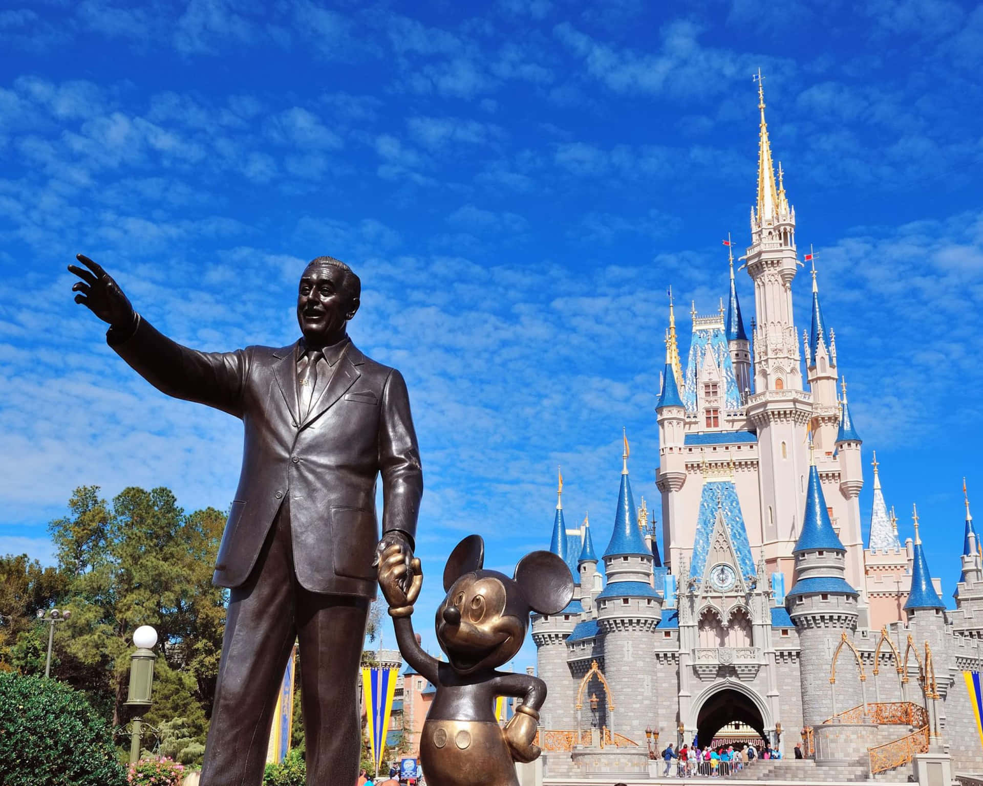 Disney World Desktop 桌布 壁紙 — 華特迪士尼和米奇老鼠的銅像矗立在標誌性的灰姑娘城堡前，天空湛藍，白雲點點。