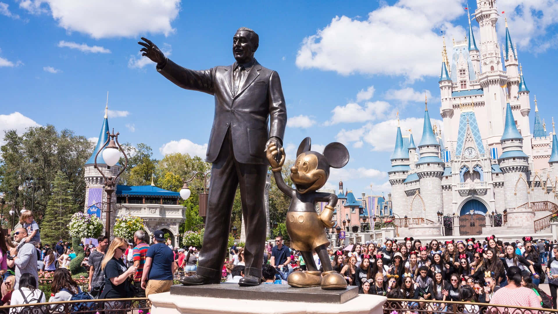 1920x1080 Disney 桌布 壁紙 — 華特迪士尼與米奇老鼠手牽手的銅像矗立在灰姑娘城堡前，背景是晴朗的藍天和零星的白雲。