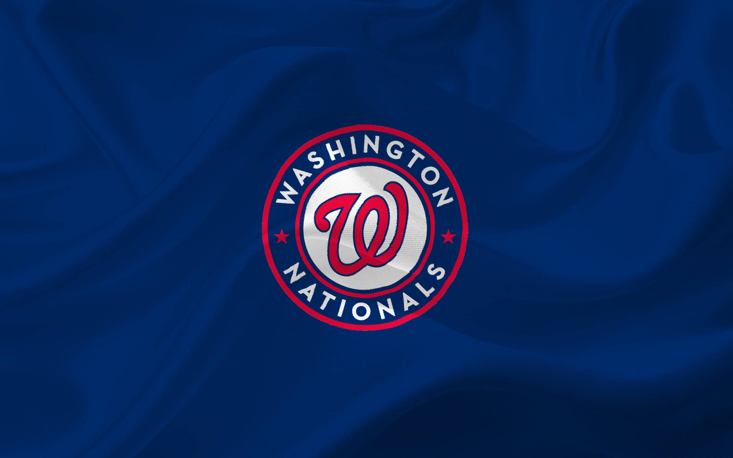 Nationals 桌布 壁紙 — 華盛頓國民隊標誌居中，置於深藍色緞面布料上，帶有流暢的褶皺和高光。