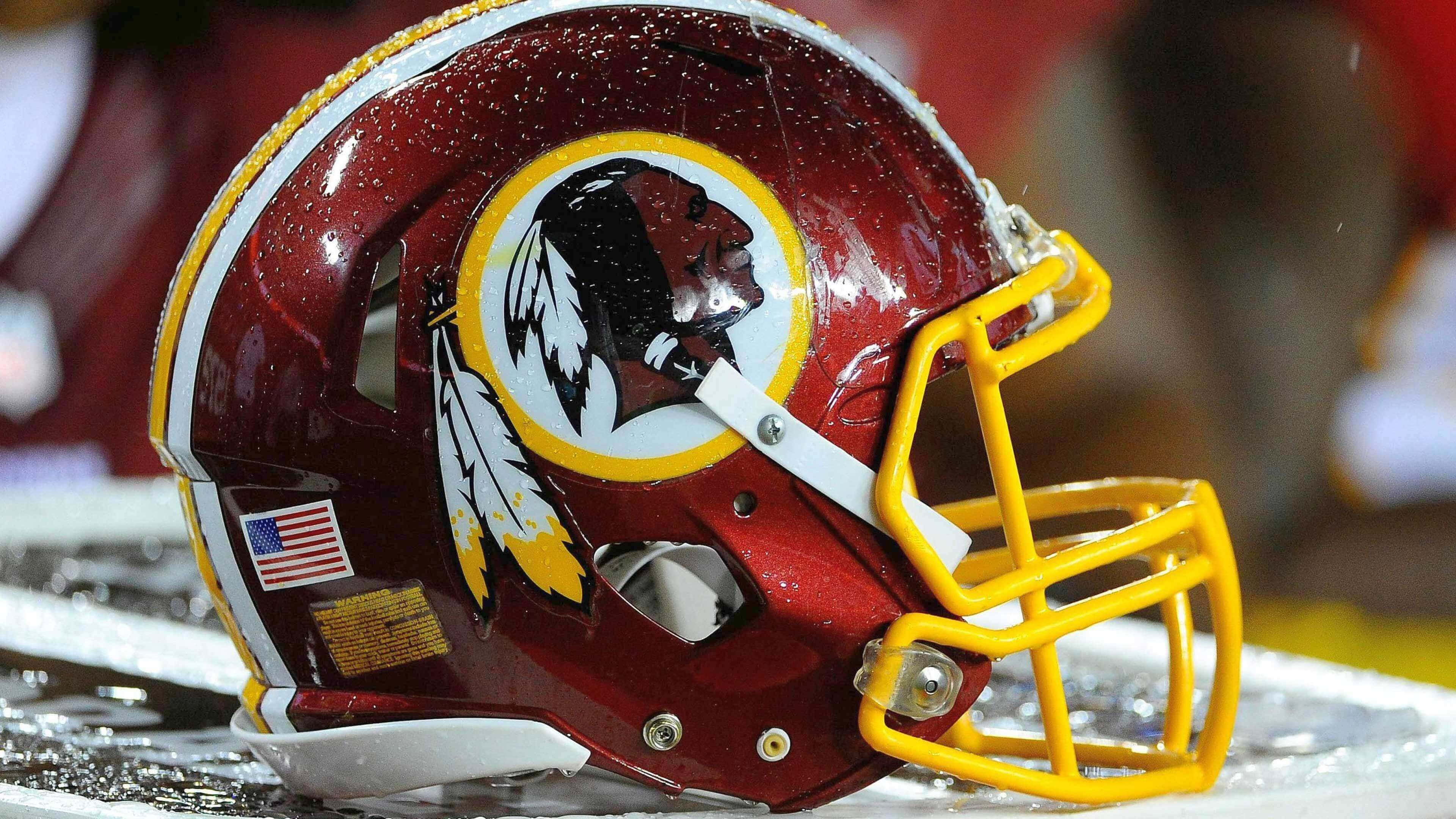 Washington Football 桌布 壁紙 — 華盛頓指揮官美式足球頭盔在潮濕場地上閃爍著雨滴的特寫。