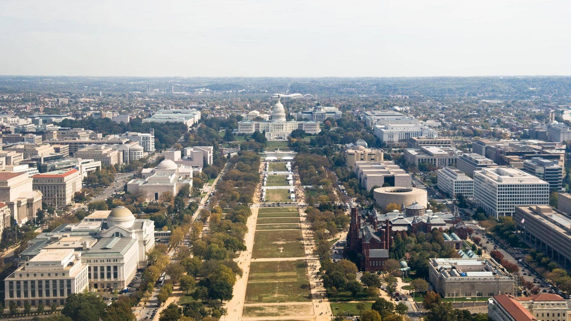 Washington 桌布 壁紙 — 華盛頓特區國家廣場的鳥瞰圖，倒影池盡頭是美國國會大廈，周圍環繞著歷史建築和秋樹。