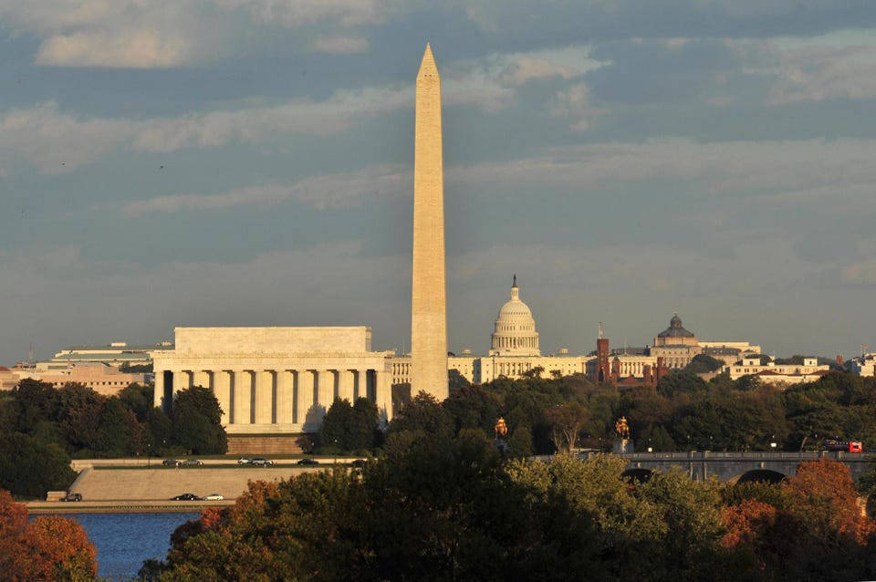 Washington Monument 桌布 壁紙 — 華盛頓紀念碑、林肯紀念堂和國會大廈在秋樹環繞下，雄偉地聳立在部分多雲的天空中。