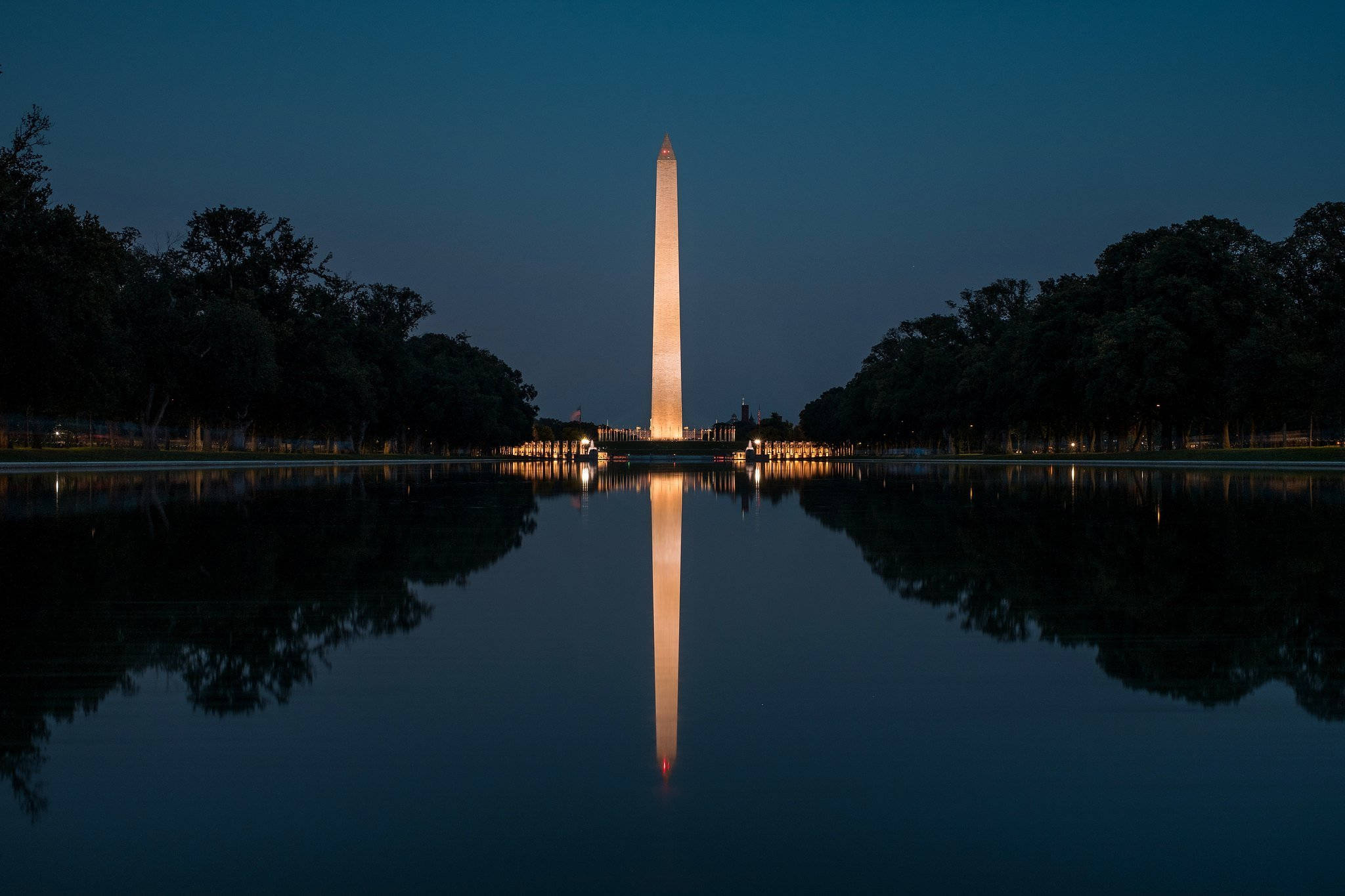 Washington 桌布 壁紙 — 華盛頓紀念碑在黃昏時溫暖地發光，其完美的倒影映照在反思池平靜的水面上。