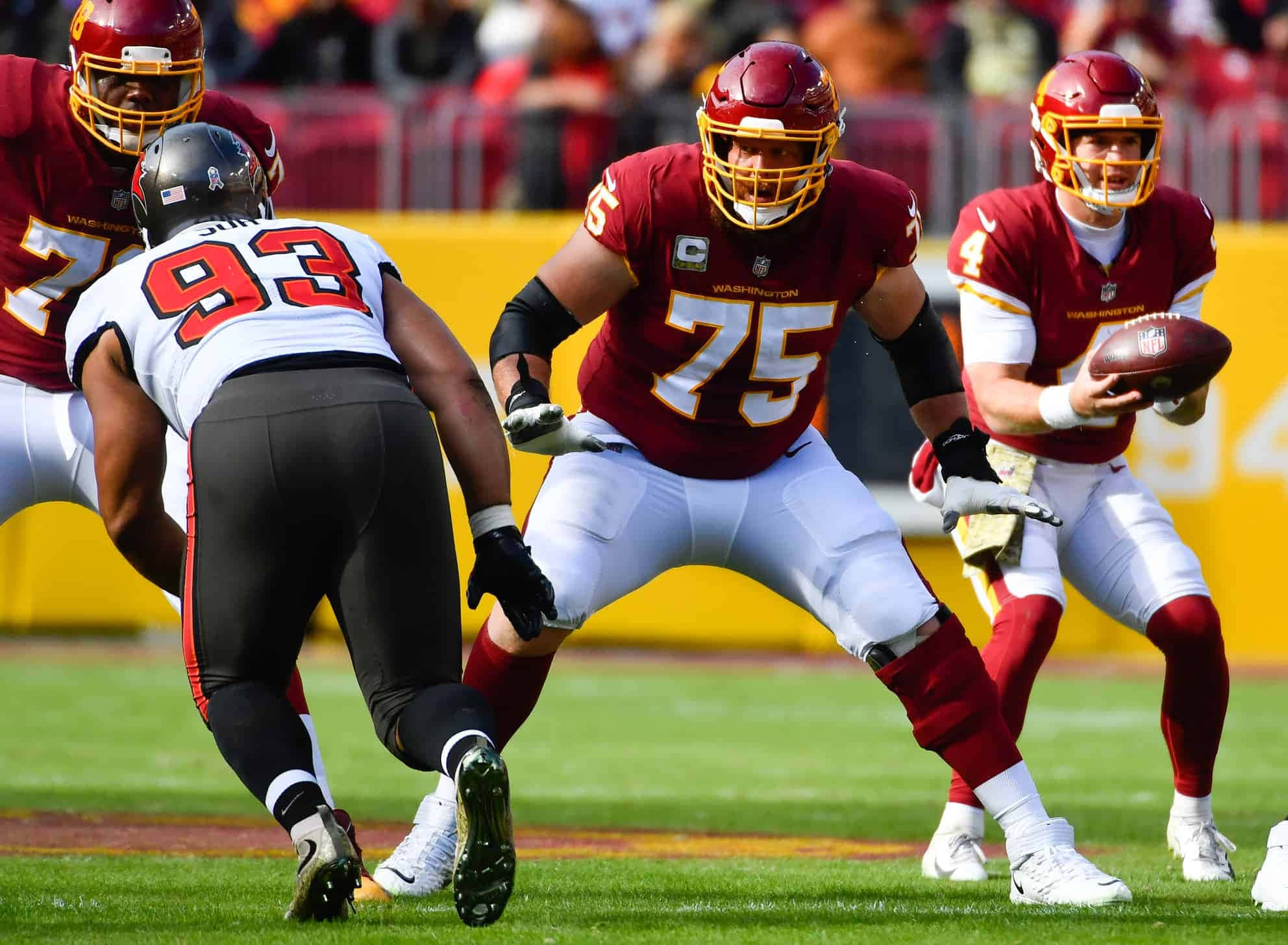 Washington Football 桌布 壁紙 — 華盛頓美式足球隊四分衛身穿紅色球衣準備傳球，而線衛和坦帕灣黑白球衣的防守球員在鮮綠色場地上交鋒。